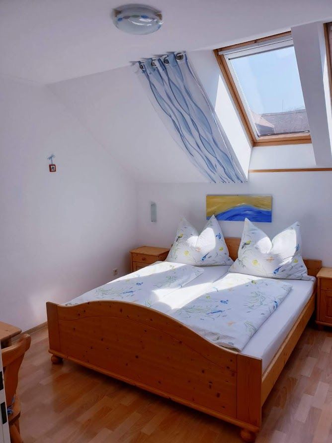 Helles Schlafzimmer mit Holzbett, Dachfenster und blauer Dekoration.