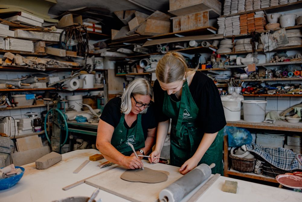 Zwei Frauen arbeiten an einem Tonstück in einer Keramikwerkstatt.