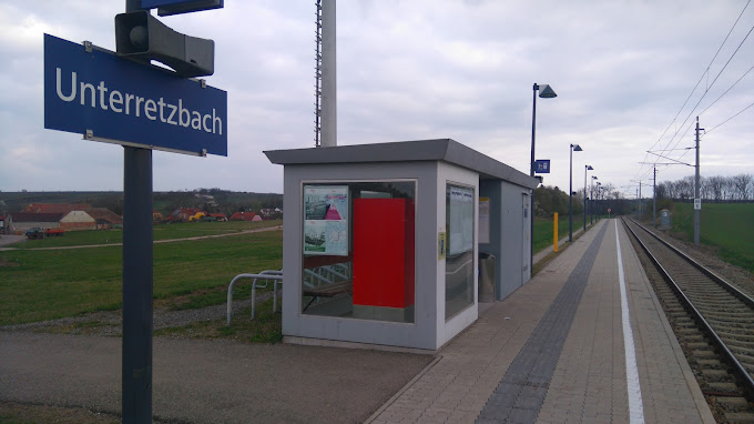 Kleiner Bahnhof Unterretzbach mit Wartehäuschen und Bahngleisen.