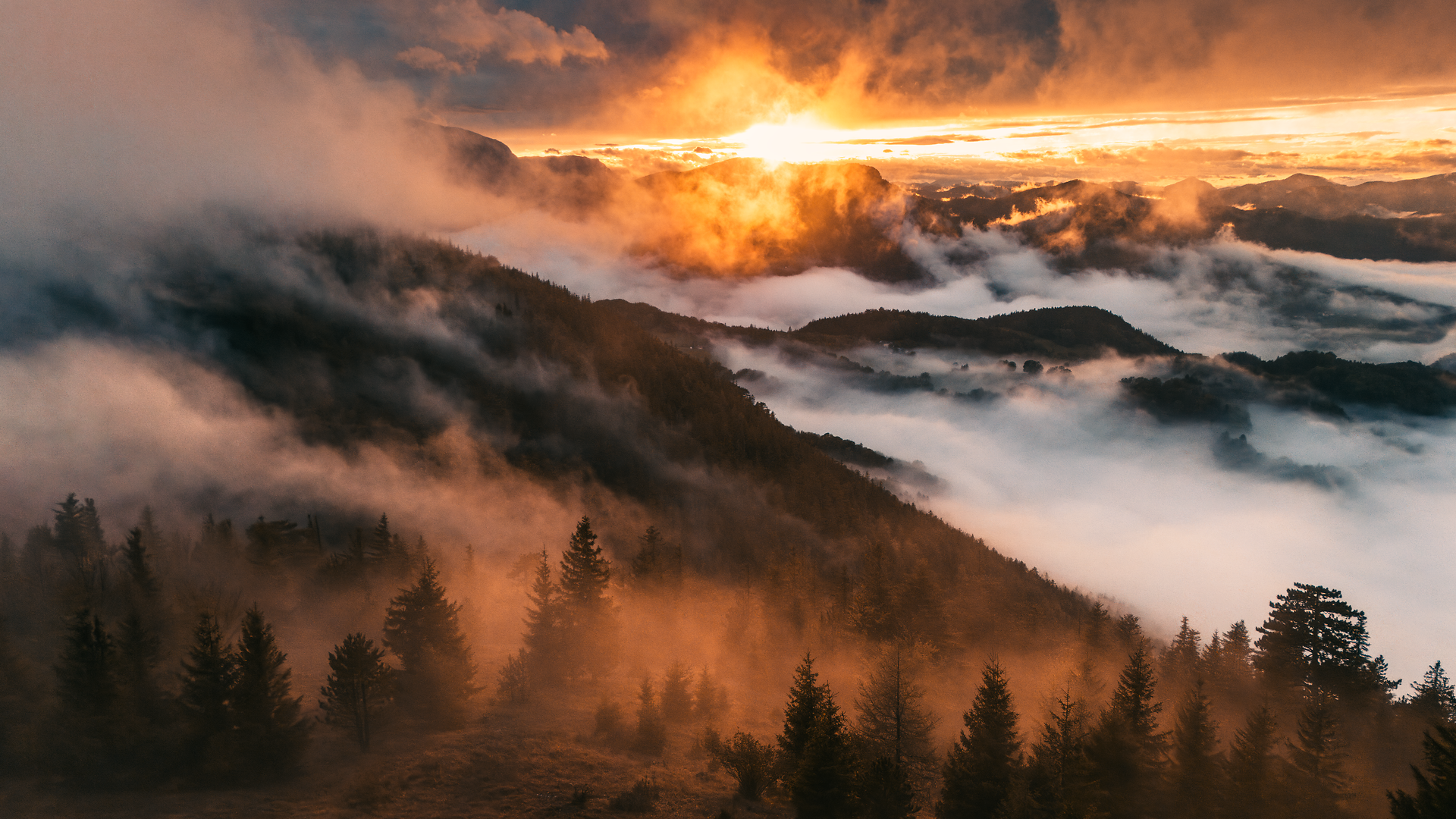 Die sanften Hügel der Wiener Alpen sind in ein mystisches Nebelmeer gehüllt, während die untergehende Sonne den Himmel in warmen Gold- und Orangetönen erleuchtet. Diese zauberhafte Herbststimmung lädt dazu ein, die frische Bergluft zu genießen und die atemberaubende Aussicht zu bewundern.