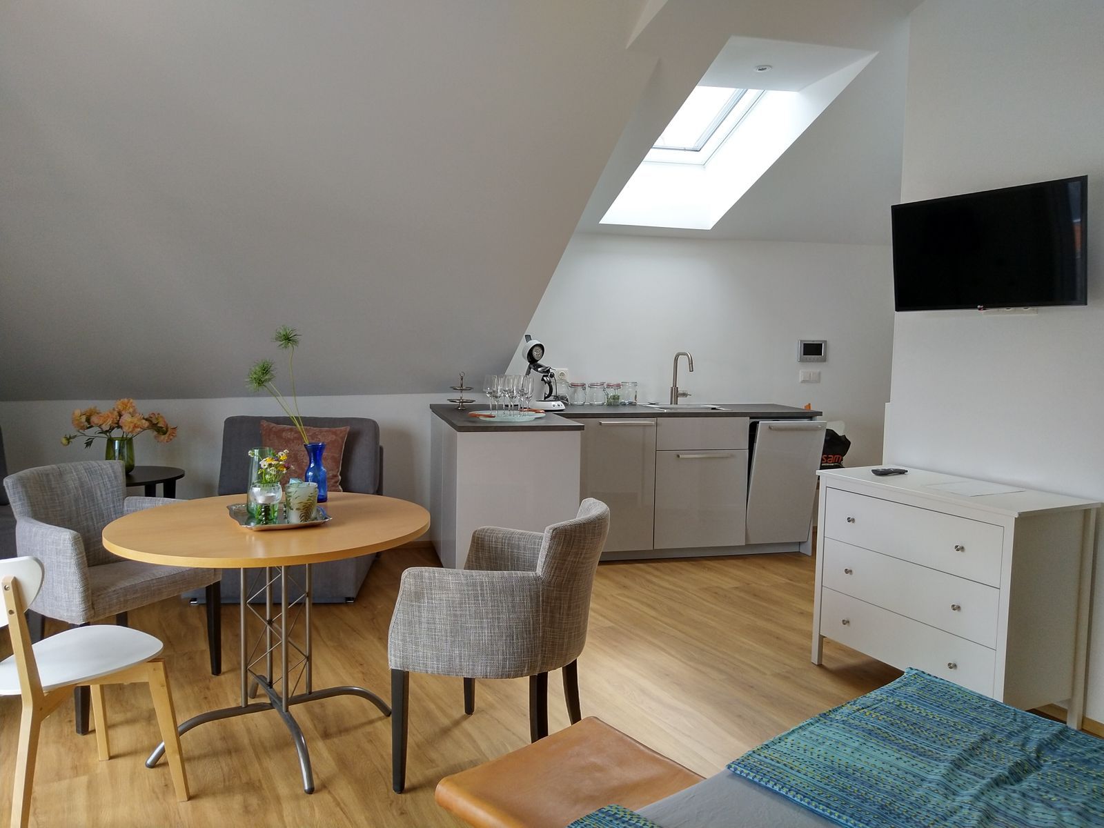 Modernes Apartment mit Küchenzeile, Esstisch und Fernseher.