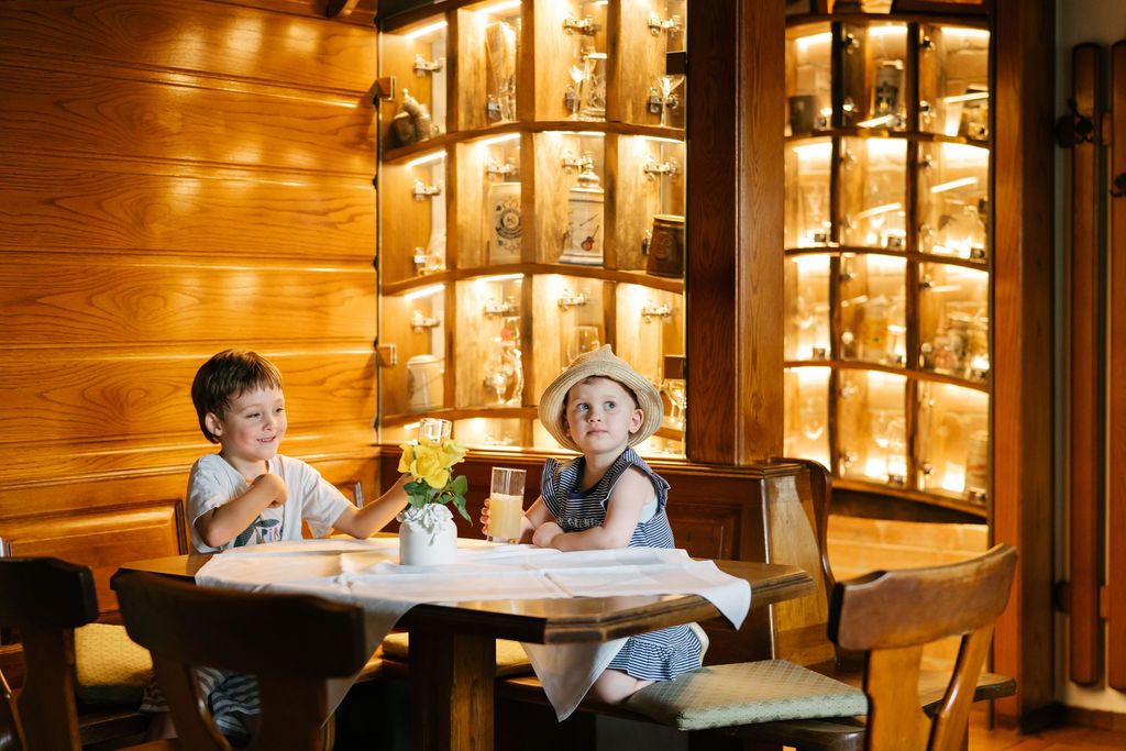 Zwei Kinder sitzen an einem Tisch in einem holzgetäfelten Restaurant.