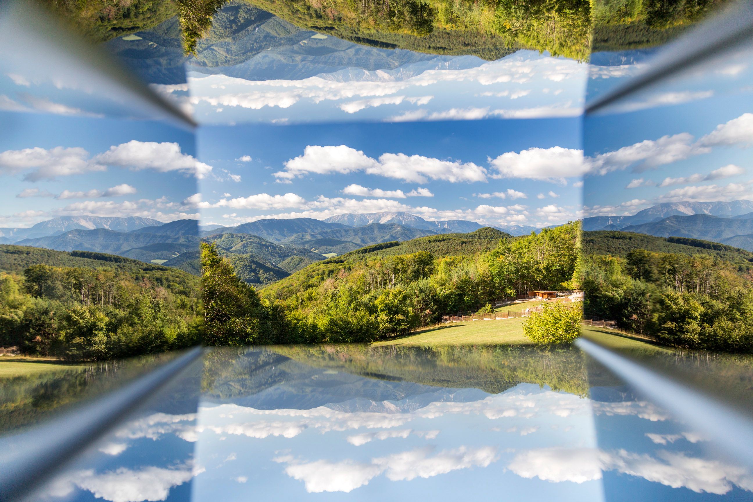 Spiegelung einer Berglandschaft mit blauem Himmel und Wolken.
