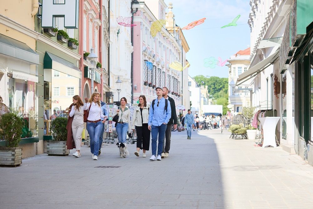 Gruppe von Menschen spaziert durch eine belebte Einkaufsstraße in St. Pölten.