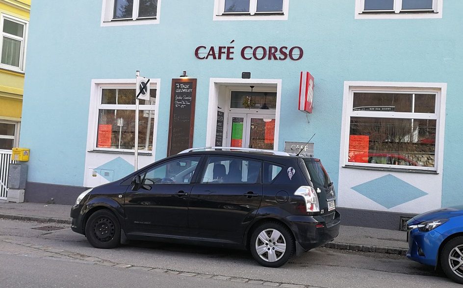 Außenansicht des Café Corso mit geparktem Auto davor.