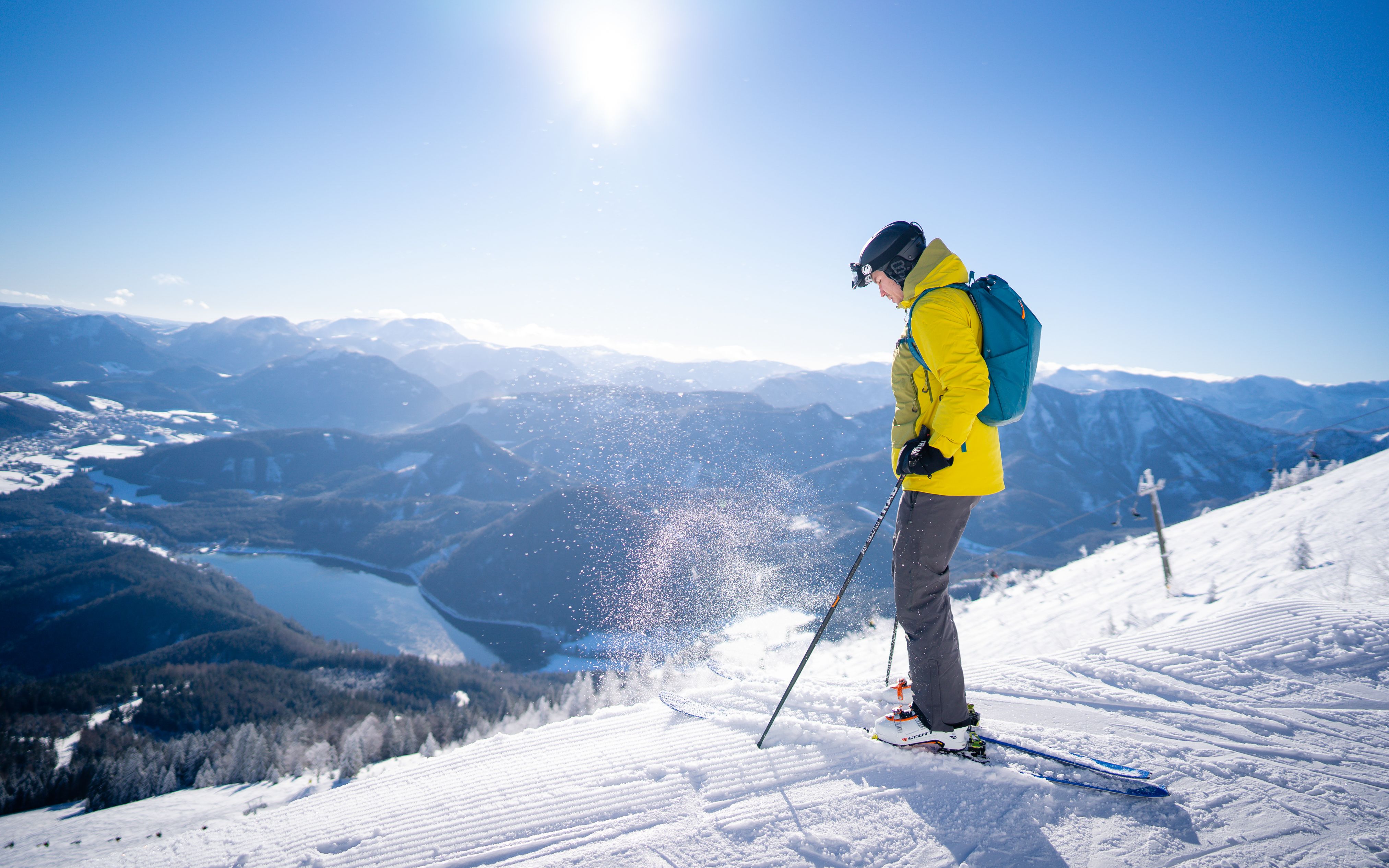 Snowboarder springt über ein gelbes Hindernis im Snowpark Gemeindealpe bei Sonnenschein.