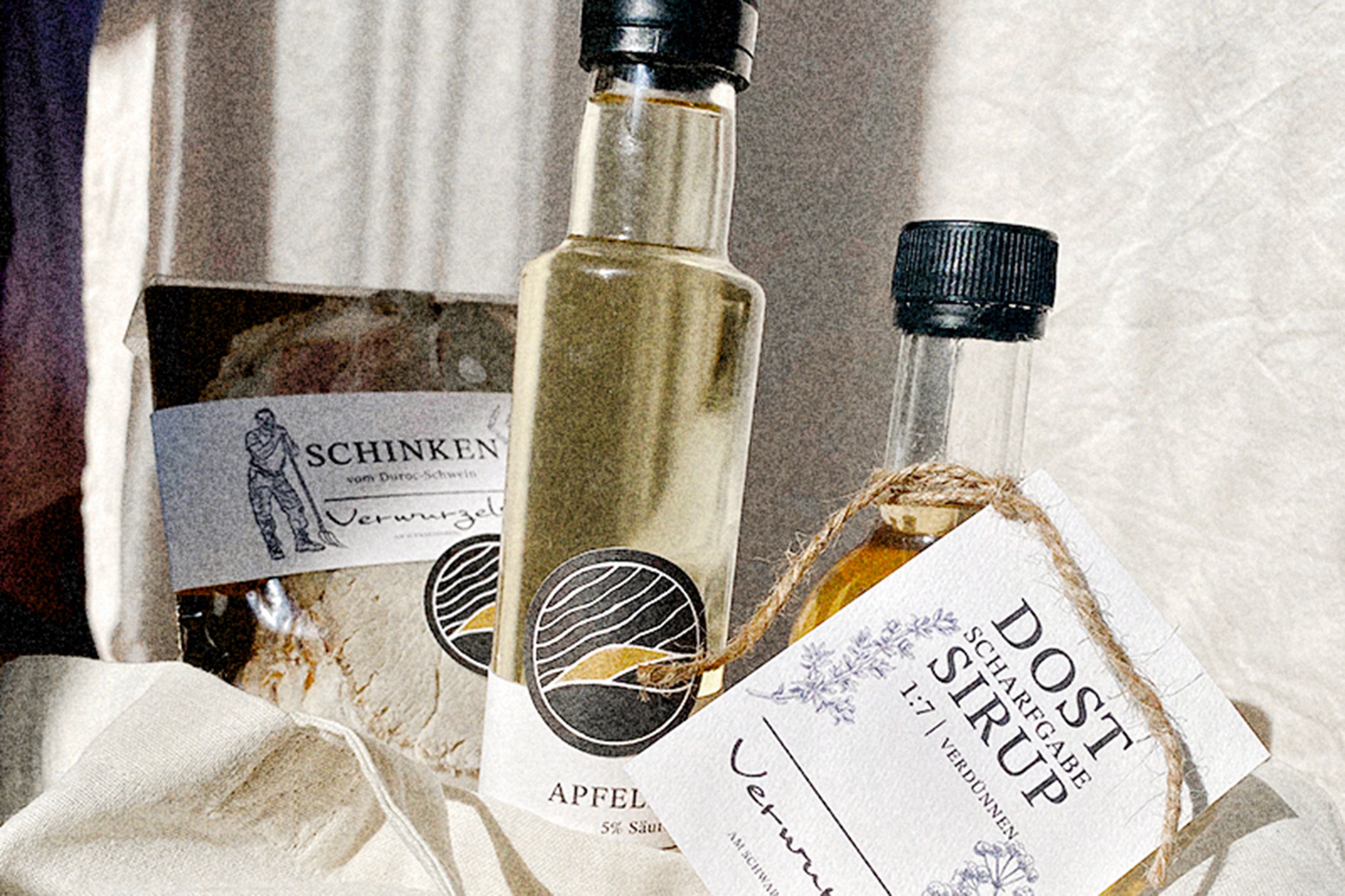 Nahaufnahme von Schinken, Apfelessig und Dost-Sirup auf einem Tuch.