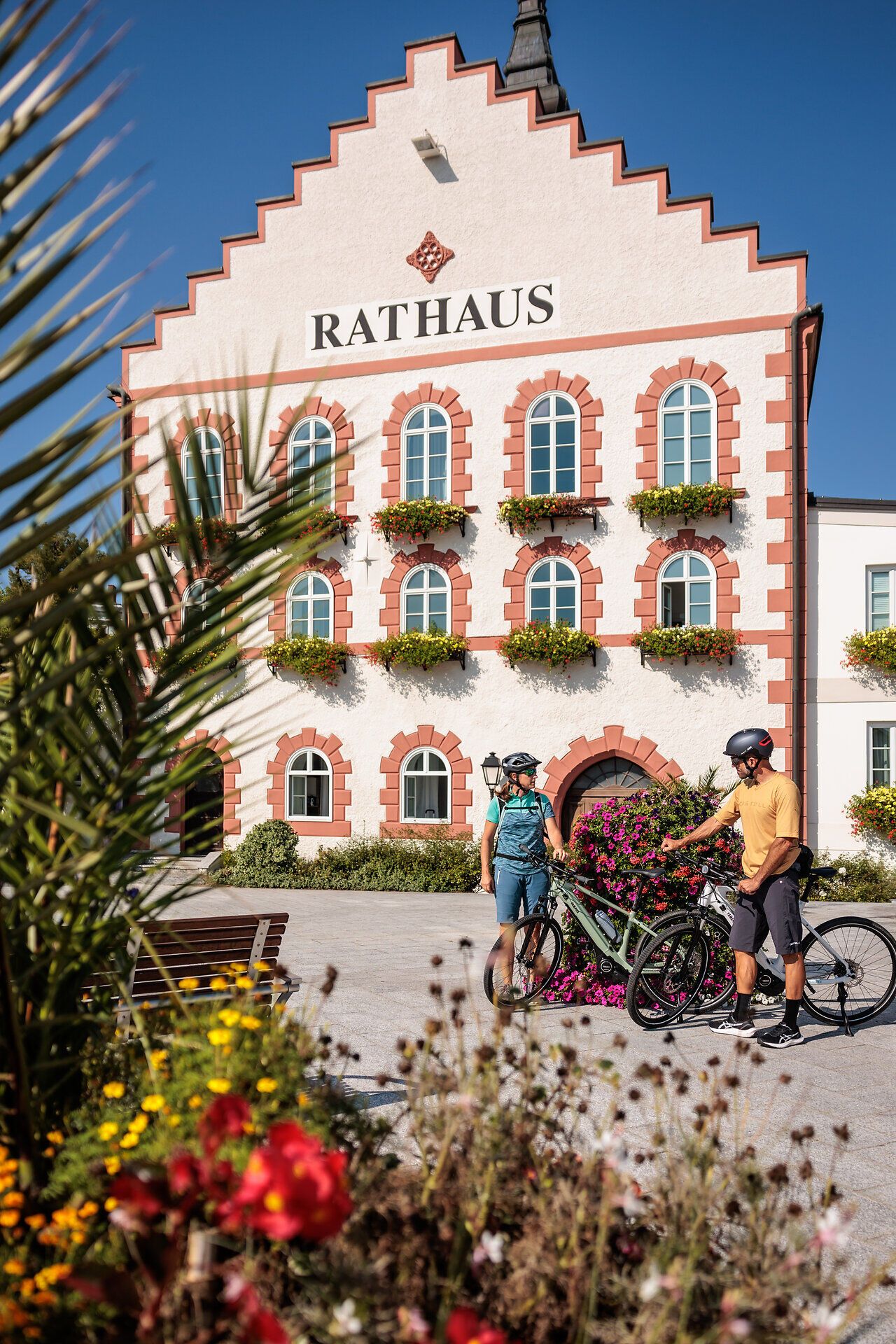 Die malerische Kulisse des Rathauses in Waidhofen lädt Radfahrer dazu ein, eine wohlverdiente Pause einzulegen. Bunte Blumenbeete umrahmen den Platz und schaffen eine einladende Atmosphäre, die den Sommer in den Bergen perfekt widerspiegelt.
