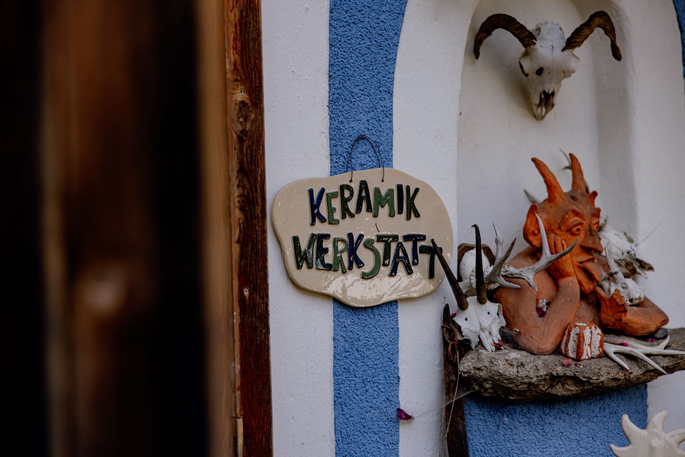 Eingang zu einer Keramikwerkstatt mit einem Schild und dekorativen Elementen.