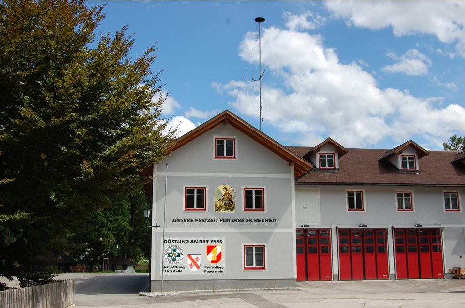 Feuerwehrgebäude mit roten Toren und Schriftzug 'Unsere Freizeit für Ihre Sicherheit'.