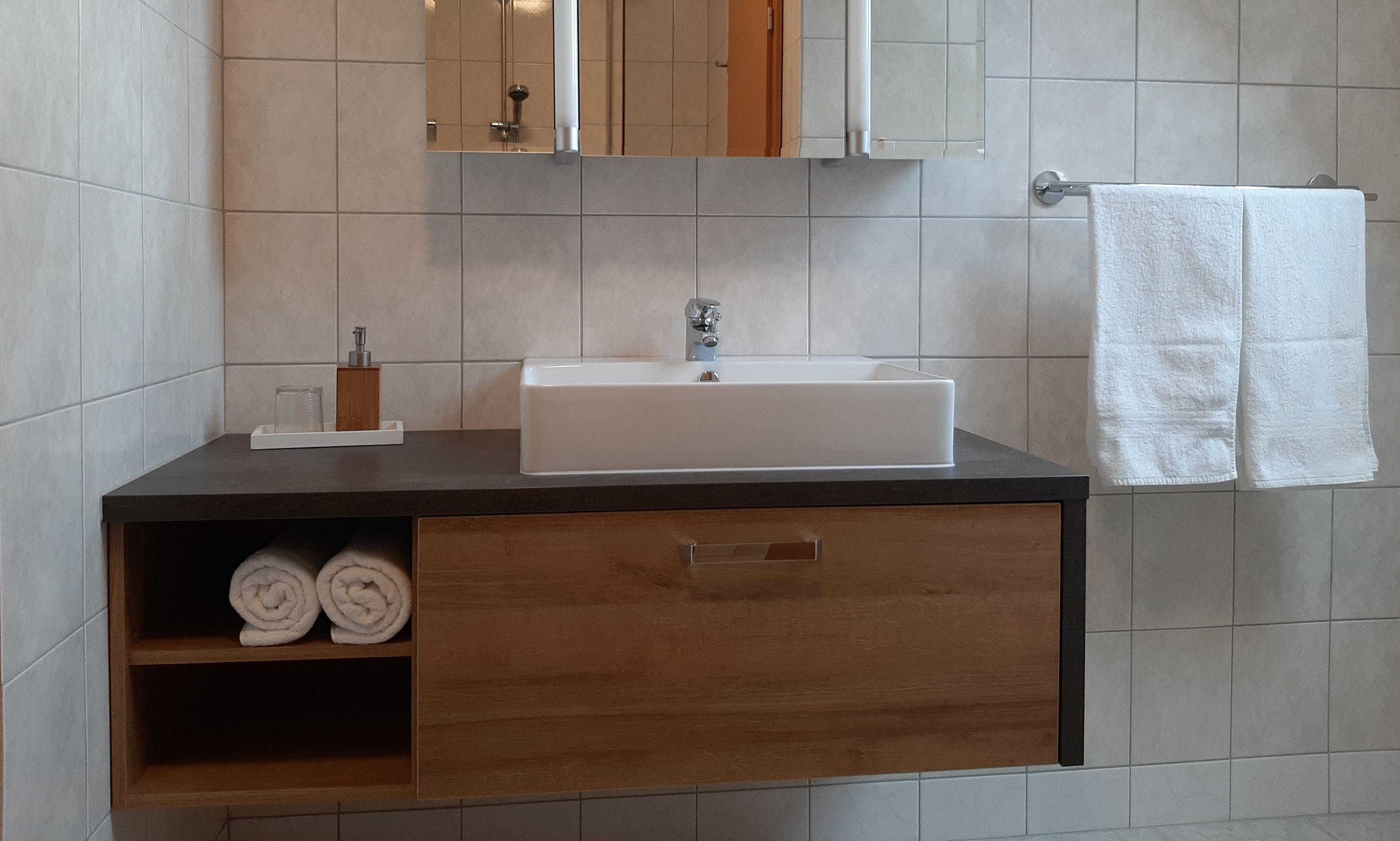 Modernes Badezimmer mit Waschbecken, Handtüchern und Spiegel.