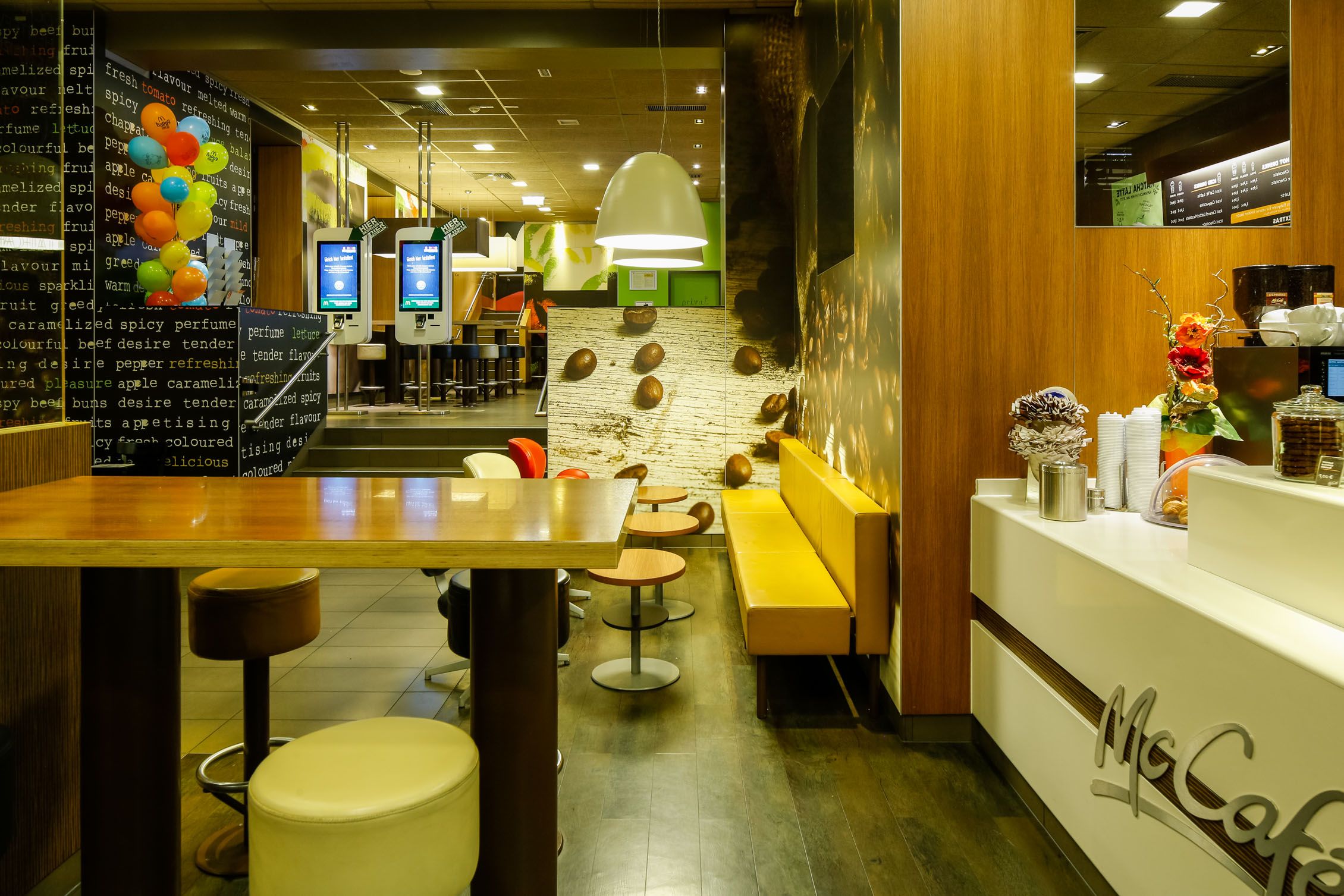 Innenansicht eines McDonald's Restaurants mit McCafé-Bereich, Sitzgelegenheiten und Bestellterminals.