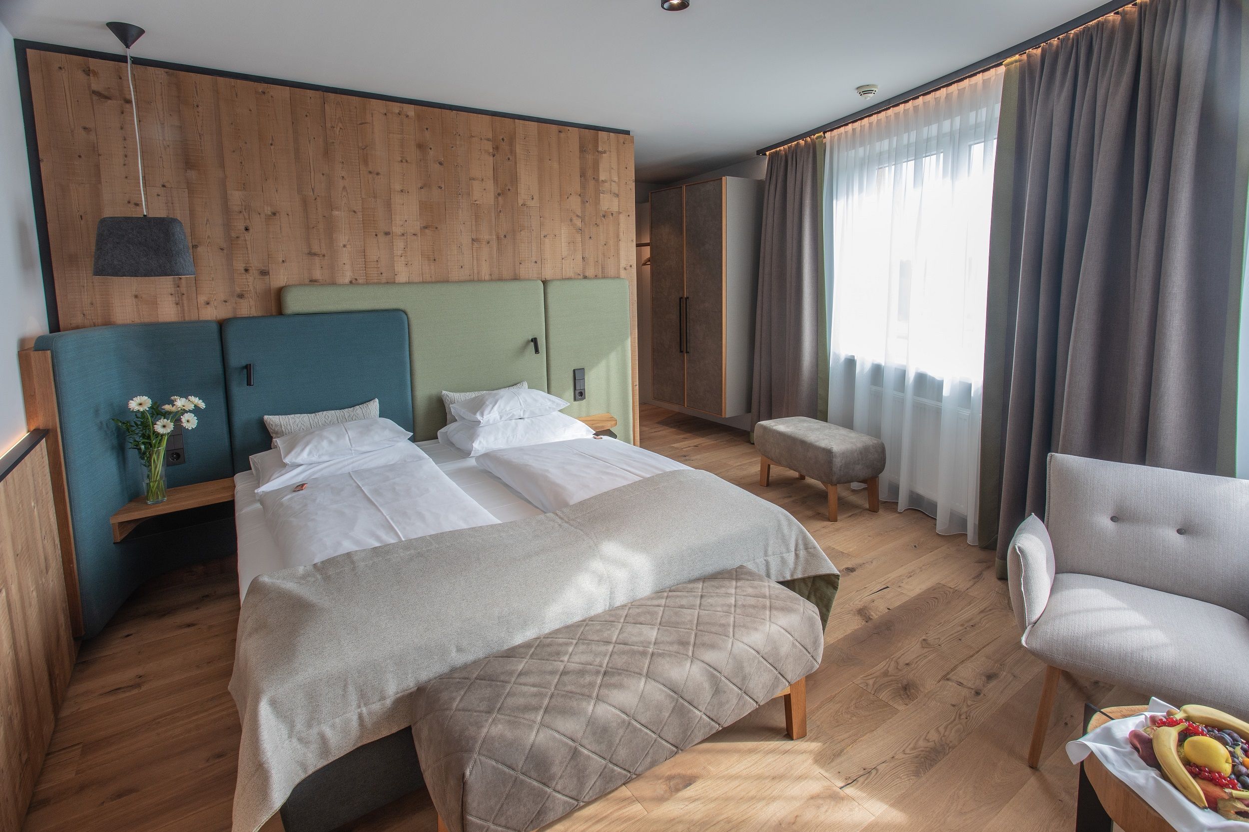 Modernes Hotelzimmer mit Doppelbett, Holzwänden und großen Fenstern.