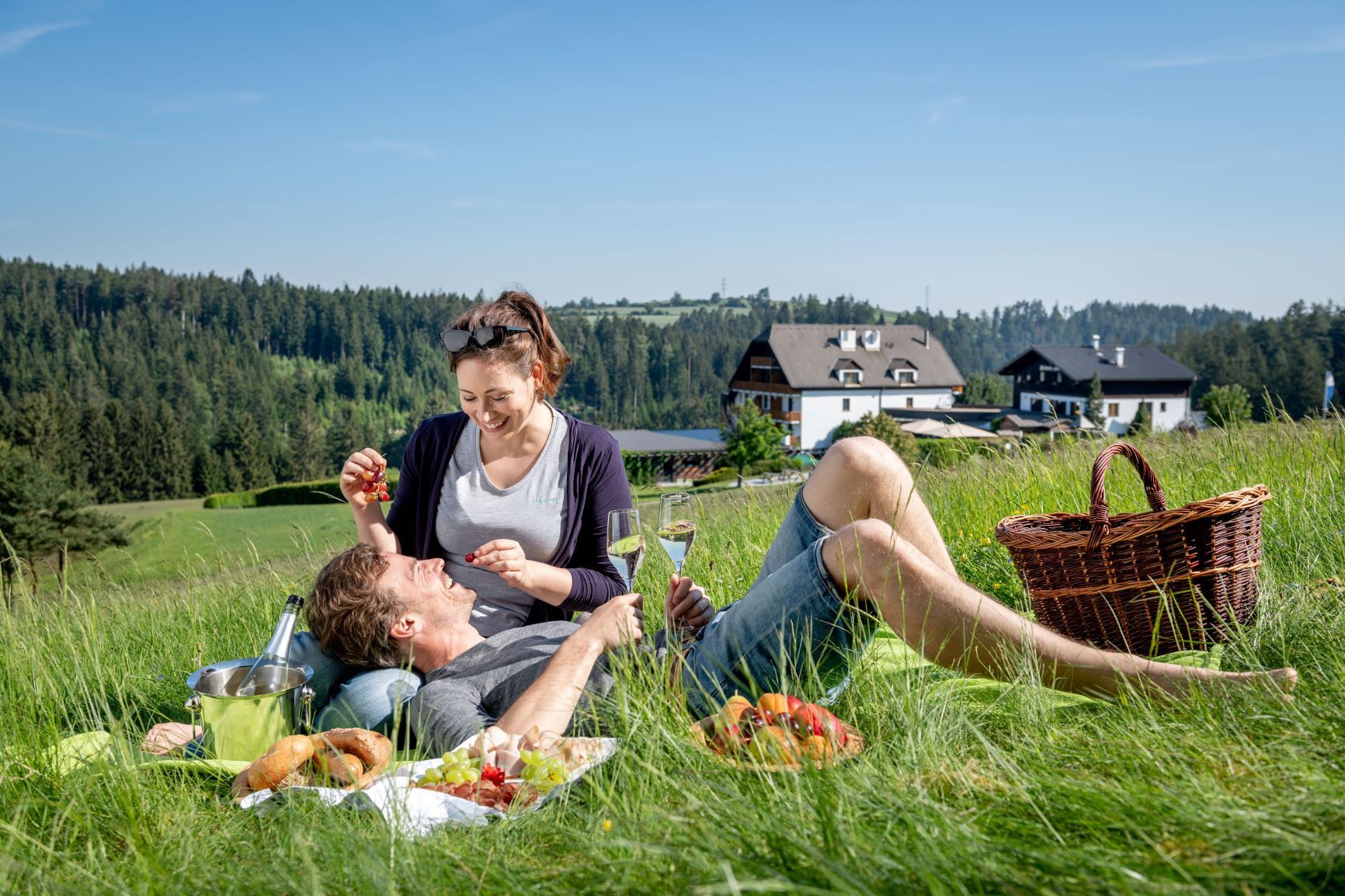 Paar beim Picknick auf einer Wiese vor dem Hotel Schwarz Alm.