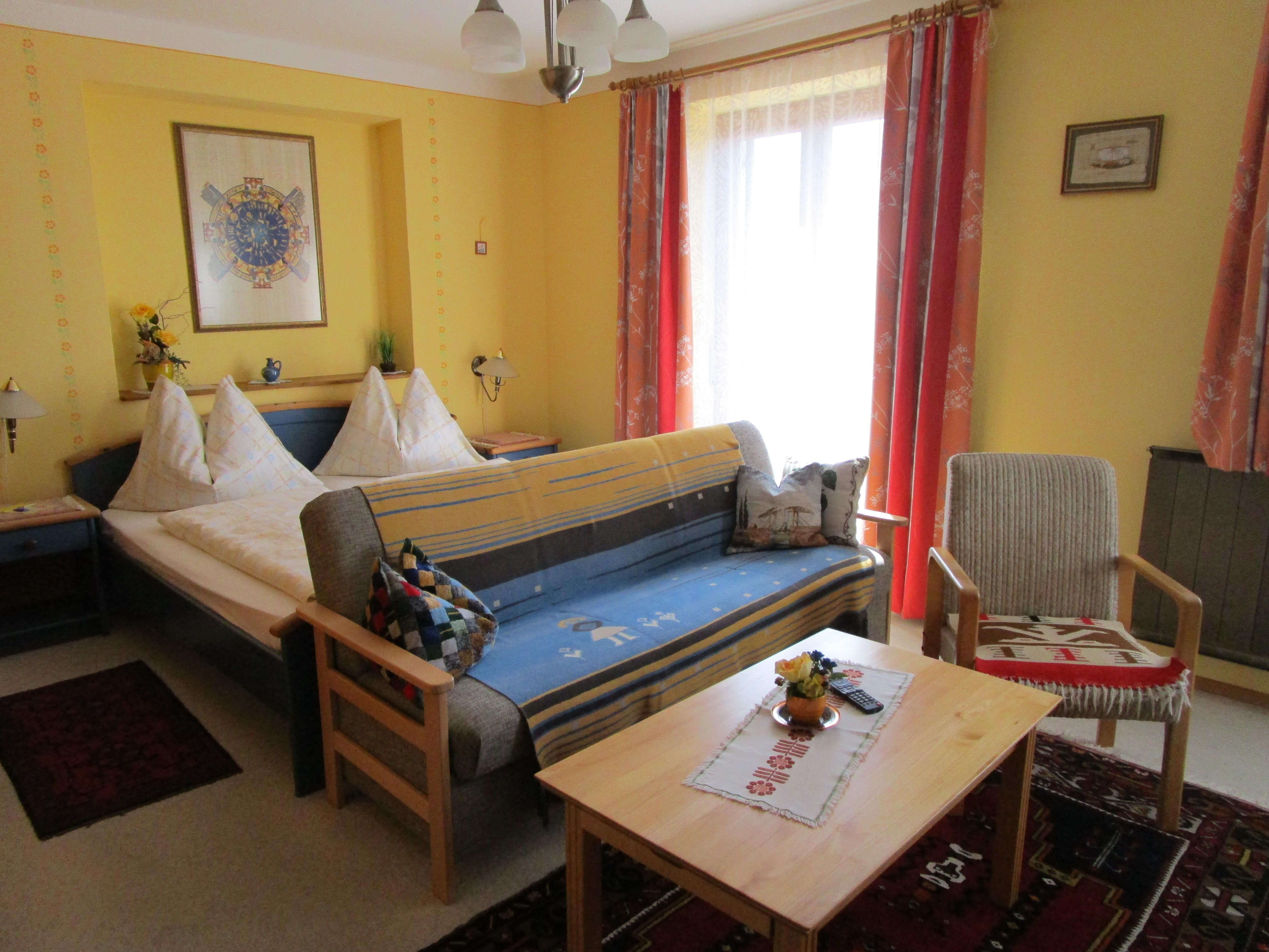 Zimmer mit Doppelbett und Couch mit Tisch im Vordergrund