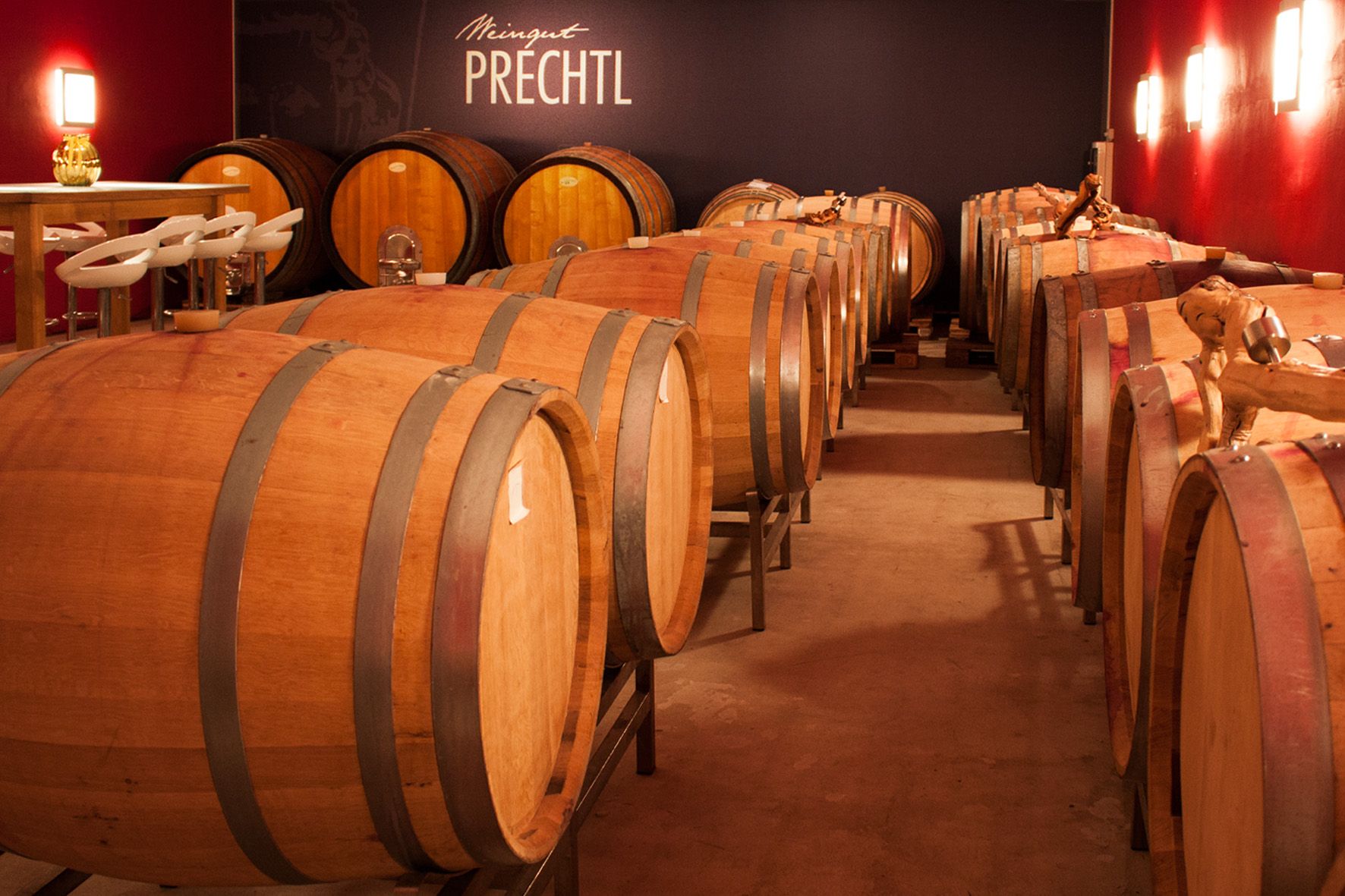 Weinkeller mit Holzfässern und Tisch mit Stühlen, Weingut Prechtl.