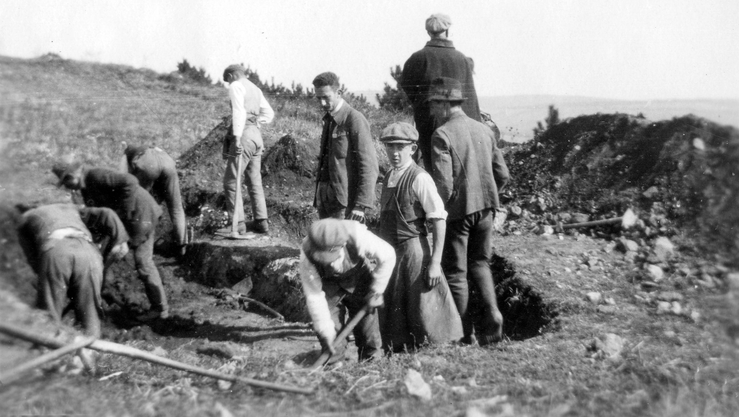 Schwarzweißfoto von Männern, die auf einem Feld graben.