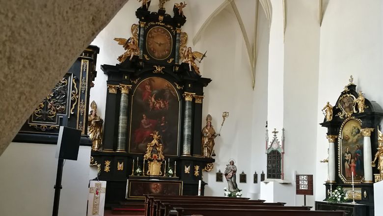 Innenansicht der Bürgerspitalskirche in Krems mit Altar und religiösen Gemälden.