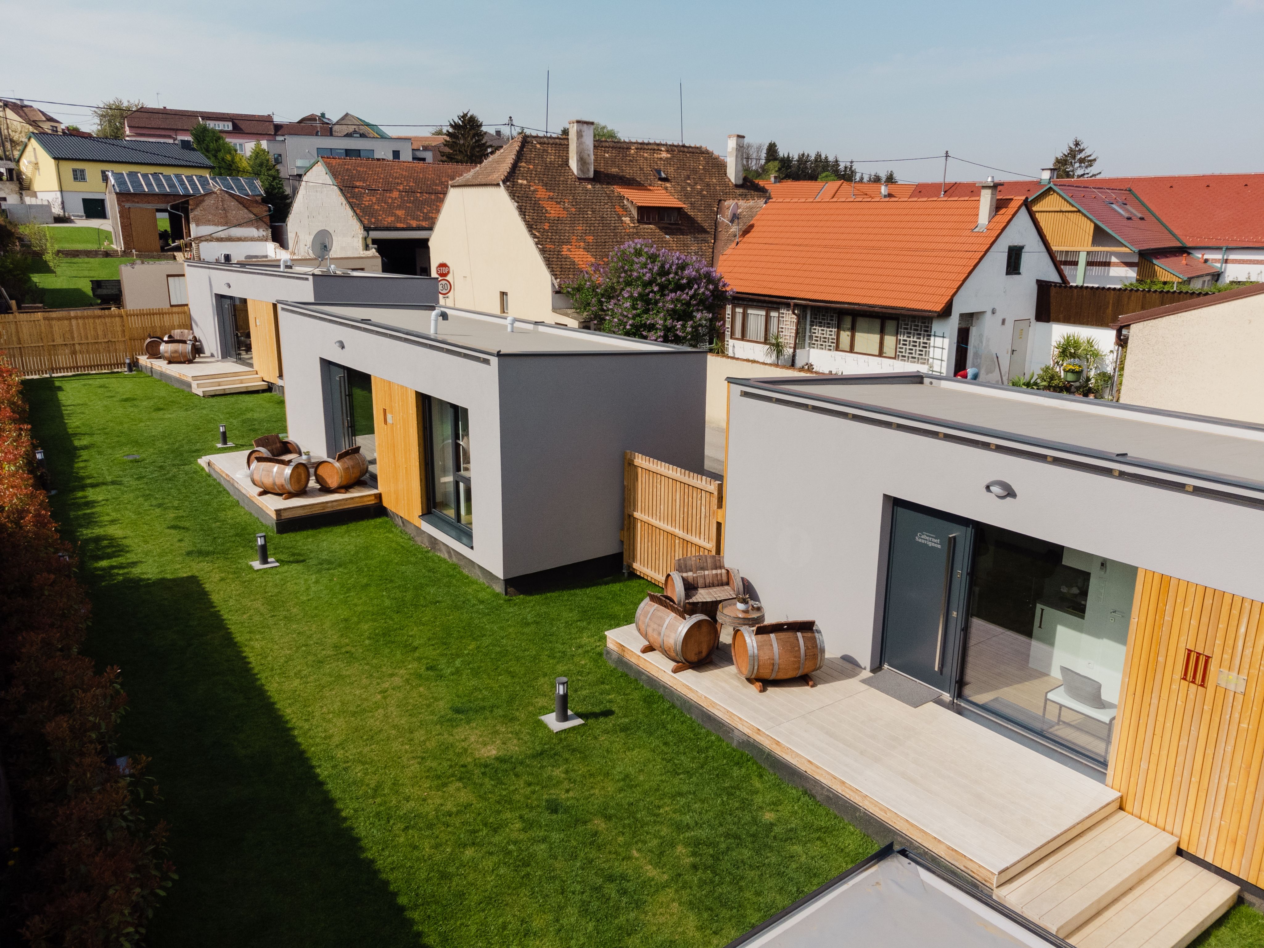 Moderne Appartements mit Holzfass-Dekoration auf grüner Wiese.