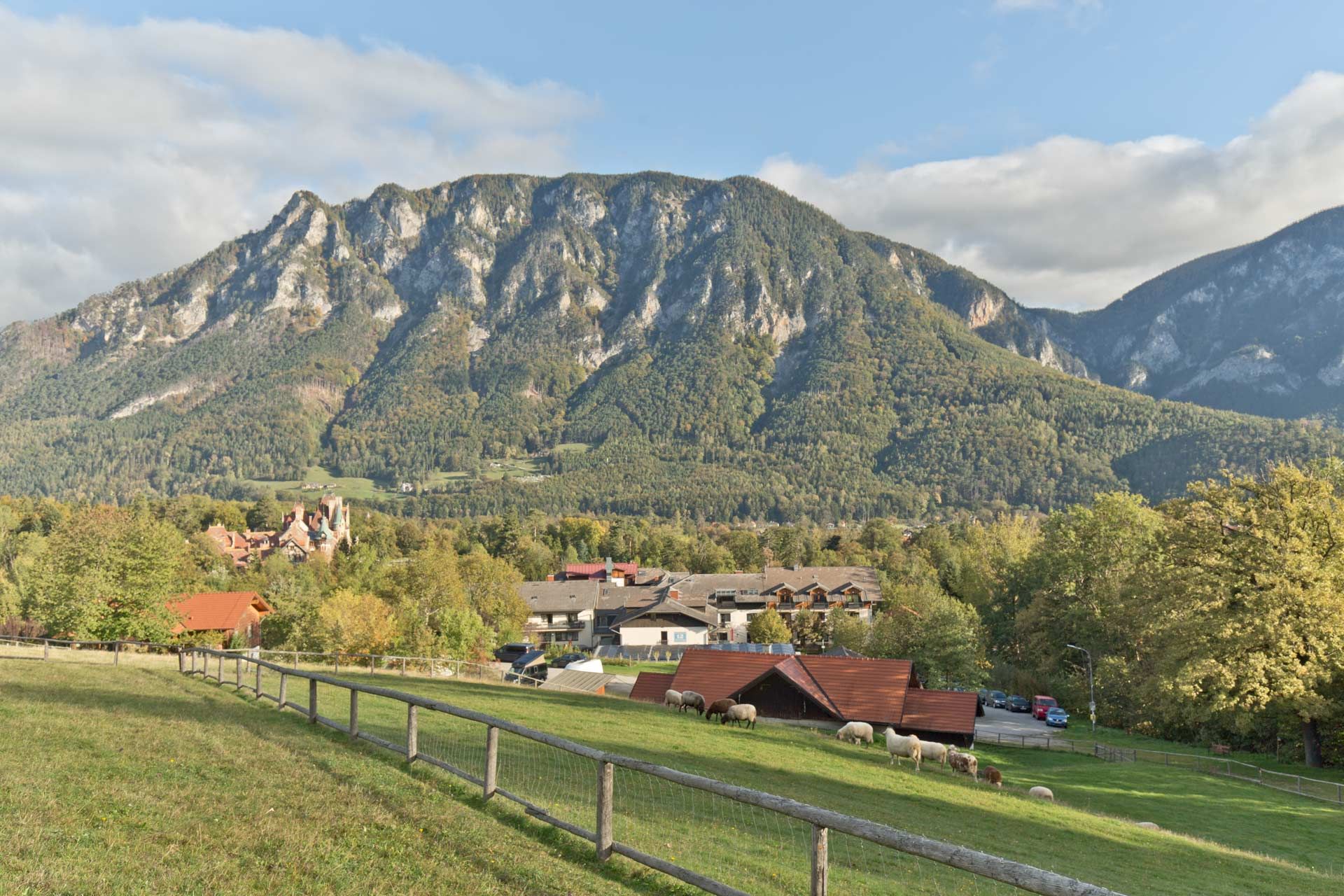 Blick auf eine grüne Weide im Vordergrund , im Hintergrund das Hotel sowei der Felsen des  Mittagssteins