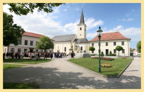 Pfarrkirche Absdorf mit umliegendem Platz und Menschenansammlung.