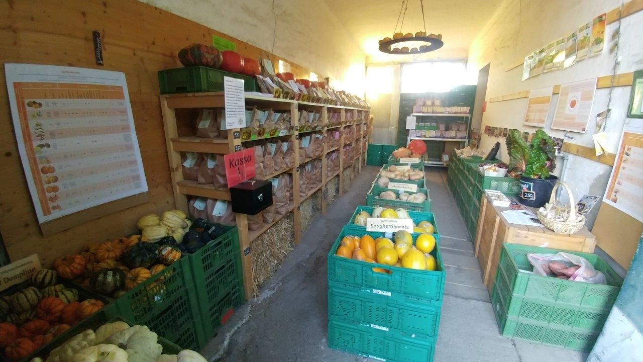 Ein kleiner Hofladen mit Regalen voller Gemüse und Produkten.