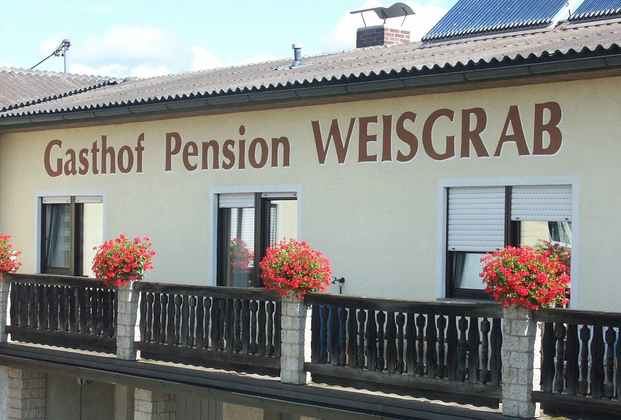 Fassade der Pension Weisgrab mit Blumenkästen auf dem Balkon.