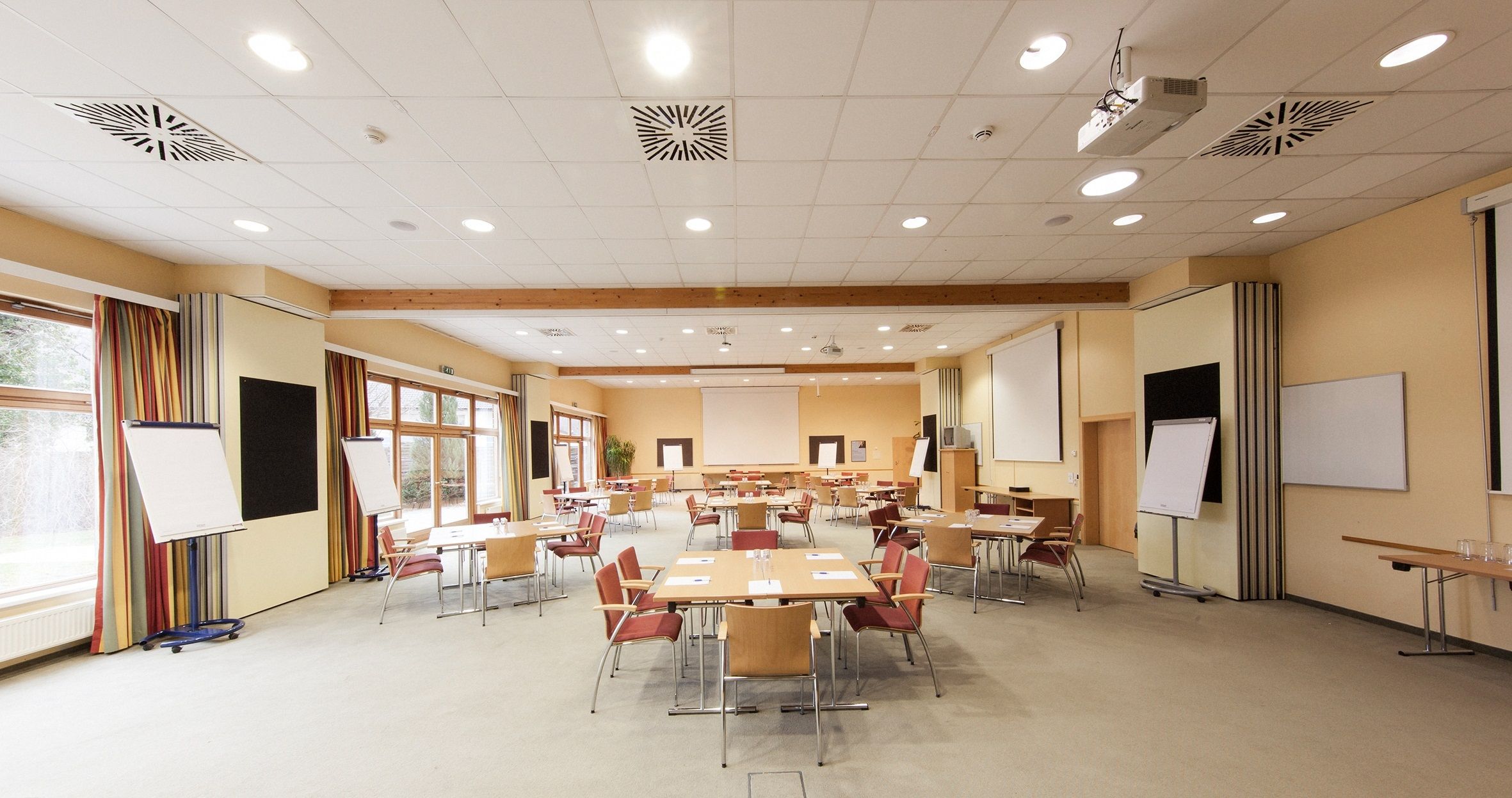 Ein leerer Konferenzraum mit Tischen, Stühlen und Flipcharts.