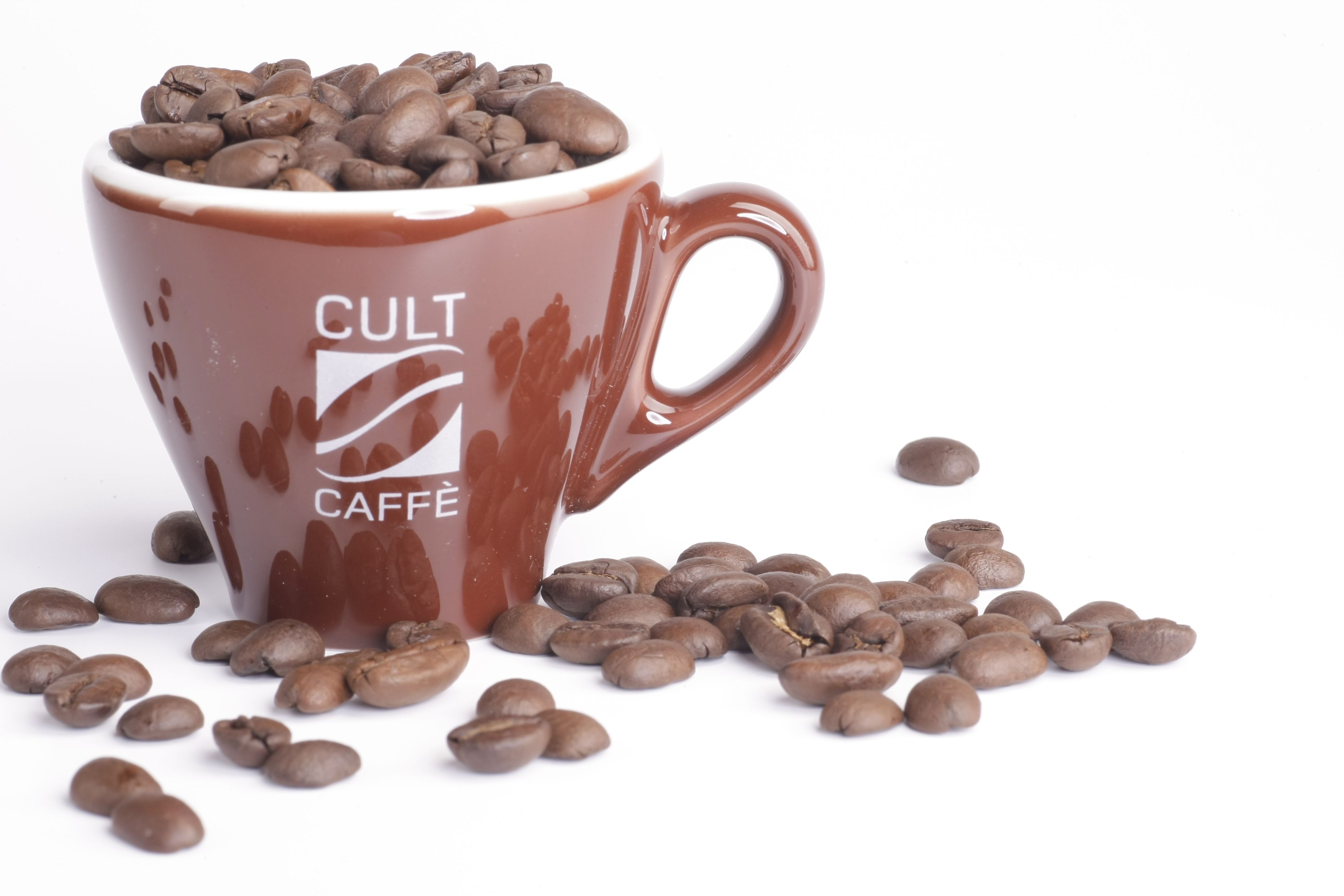 Braune Tasse mit Aufschrift 'Cult Caffè', gefüllt mit Kaffeebohnen, auf weißem Hintergrund.