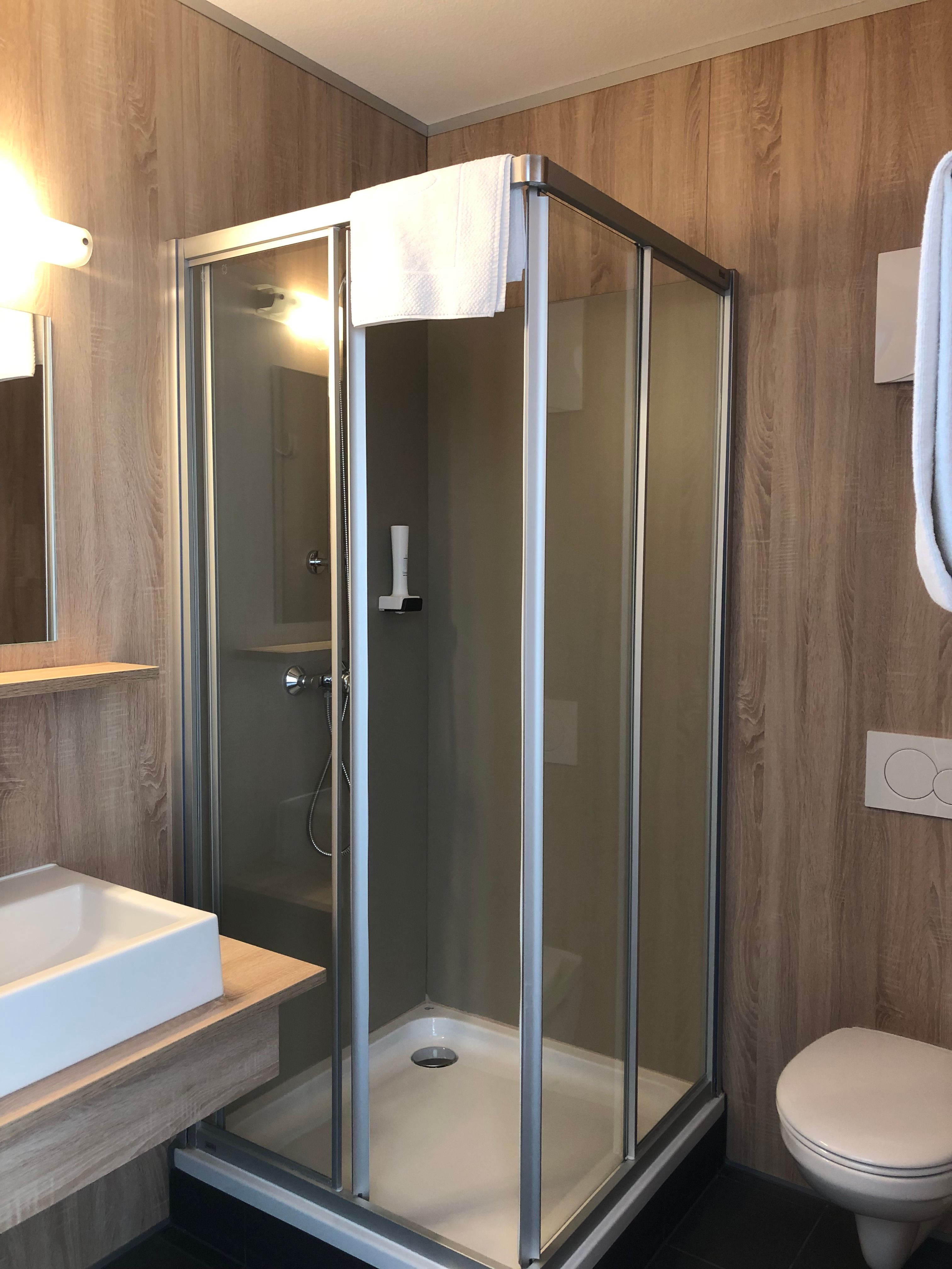 Modernes Badezimmer mit Dusche, Waschbecken und Toilette.