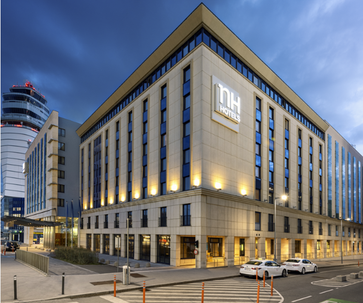 NH Vienna Airport Conference Center bei Dämmerung mit beleuchtetem Gebäude.