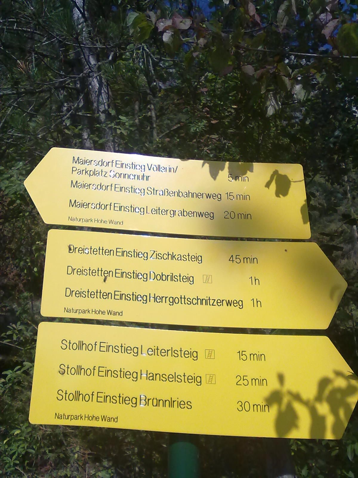 Gelbe Wegweiser im Naturpark Hohe Wand mit verschiedenen Wanderwegen und Gehzeiten.