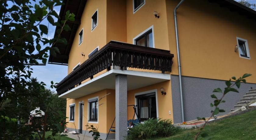 Gelbes Haus mit Balkon und Garten, umgeben von Pflanzen.
