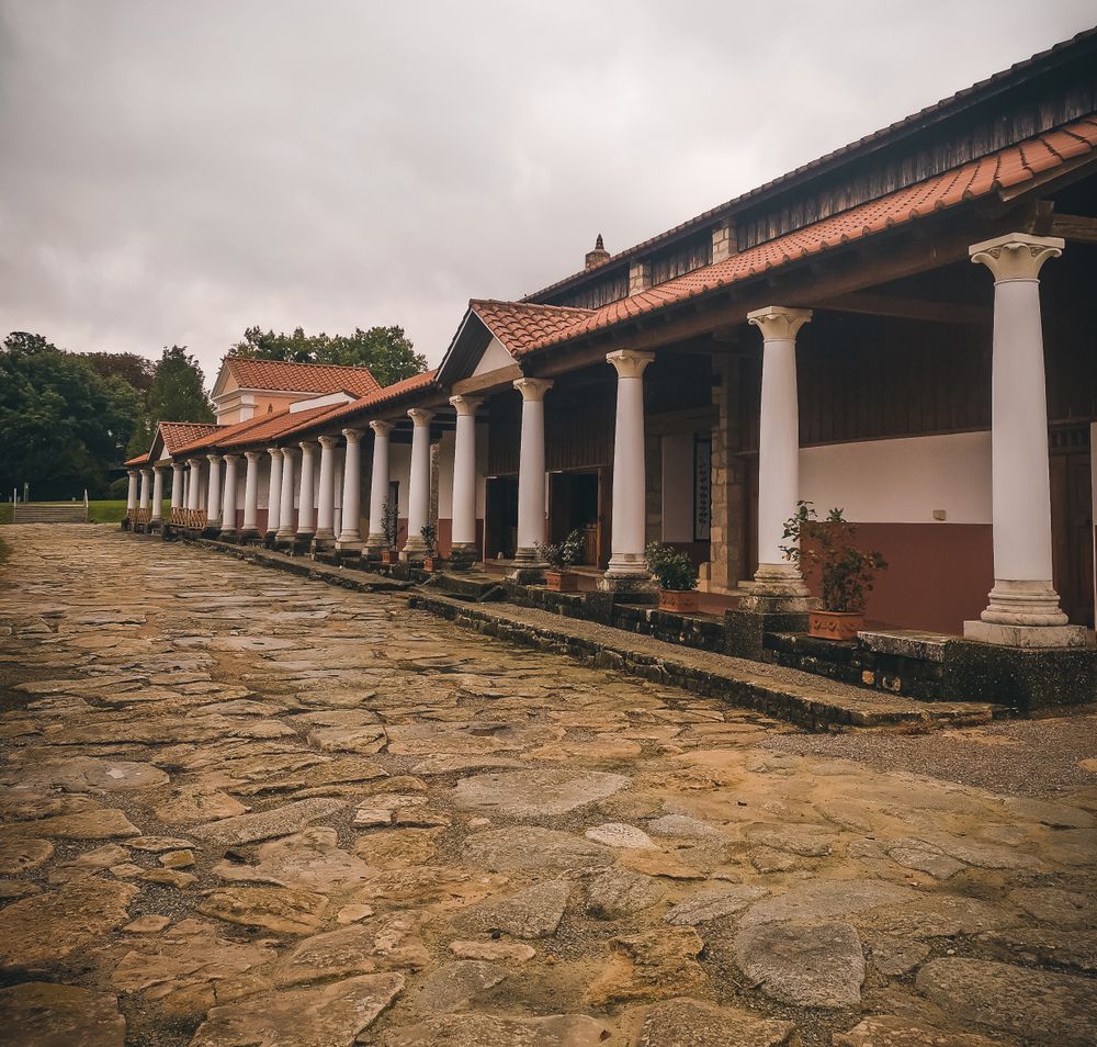 Römerstadt Carnuntum mit rekonstruierten Gebäuden und roten Dächern, umgeben von grünen Bäumen und Rasenflächen.