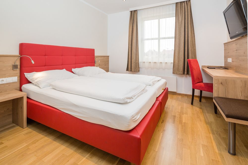 Modernes Hotelzimmer mit rotem Bett und Schreibtisch.