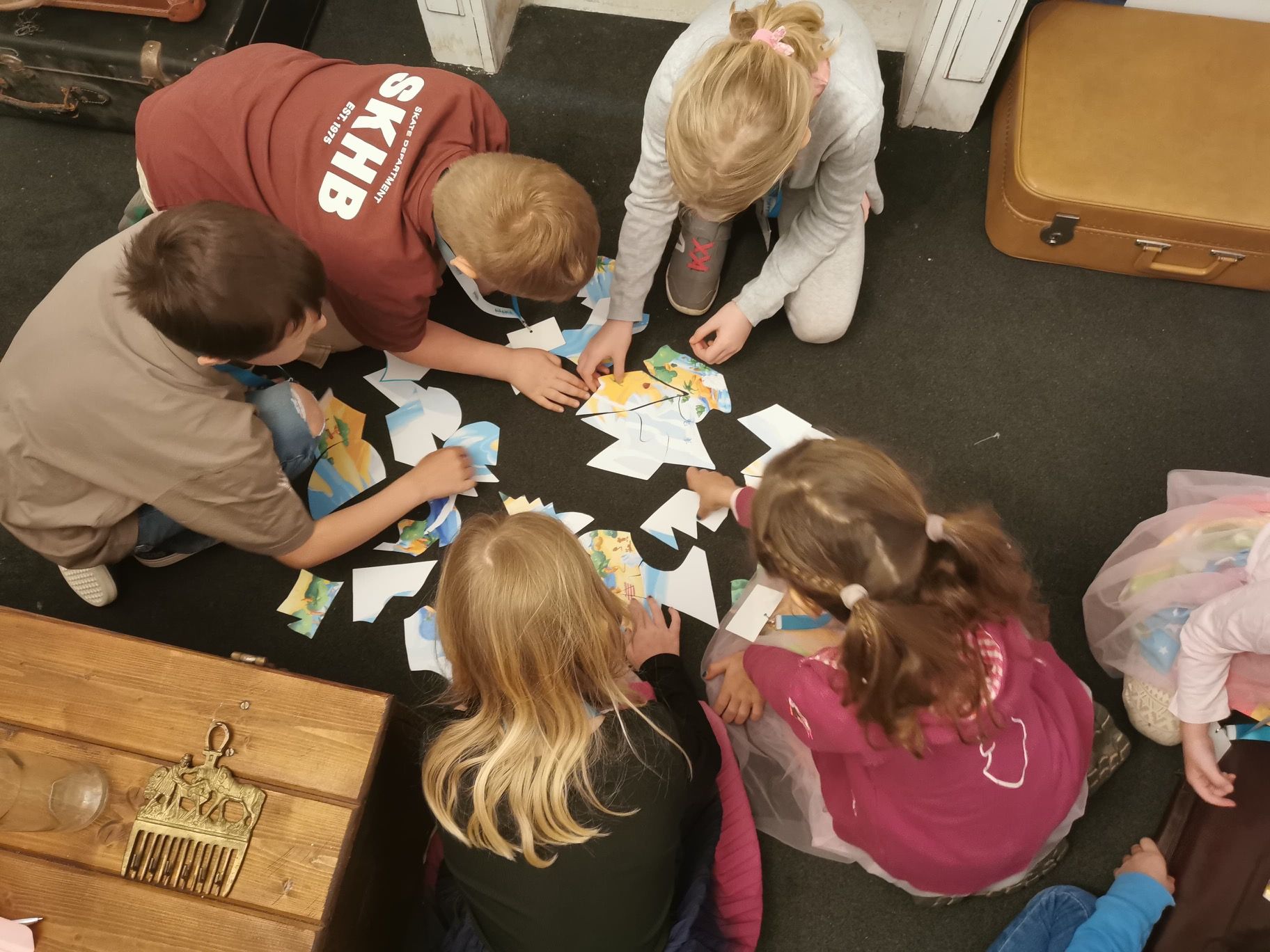 Kinder sitzen am Boden und lösen ein Rätsel 