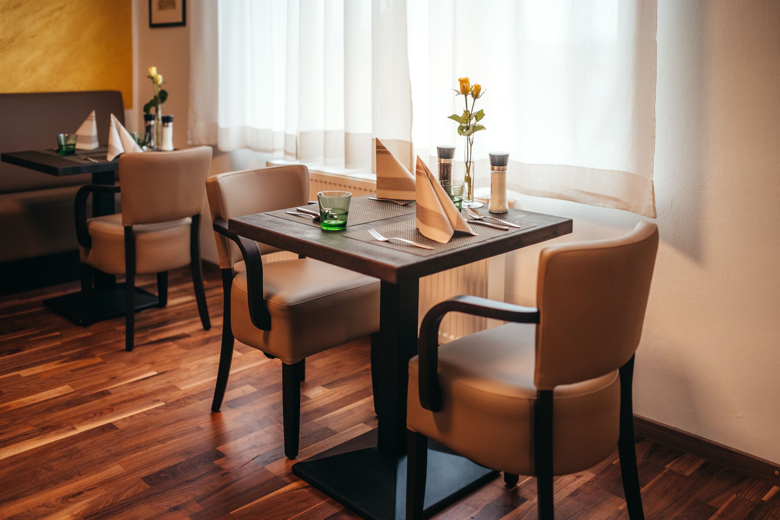 Gemütliches Restaurant mit Holzboden, gedecktem Tisch und Blumen.