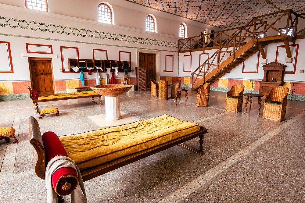 Römischer Raum mit Liegen, Stühlen und Treppe.