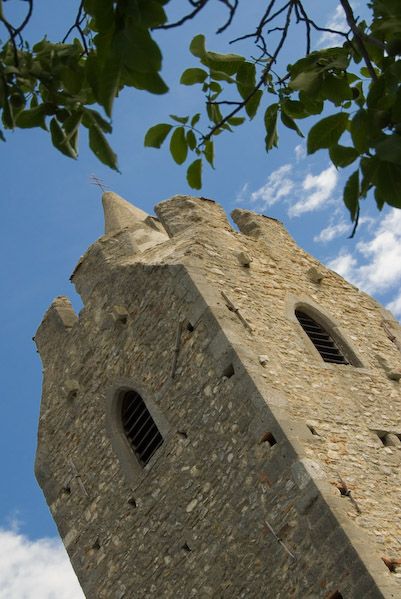 Wehrkirche Scharndorf mit blauem Himmel und Blättern im Vordergrund.