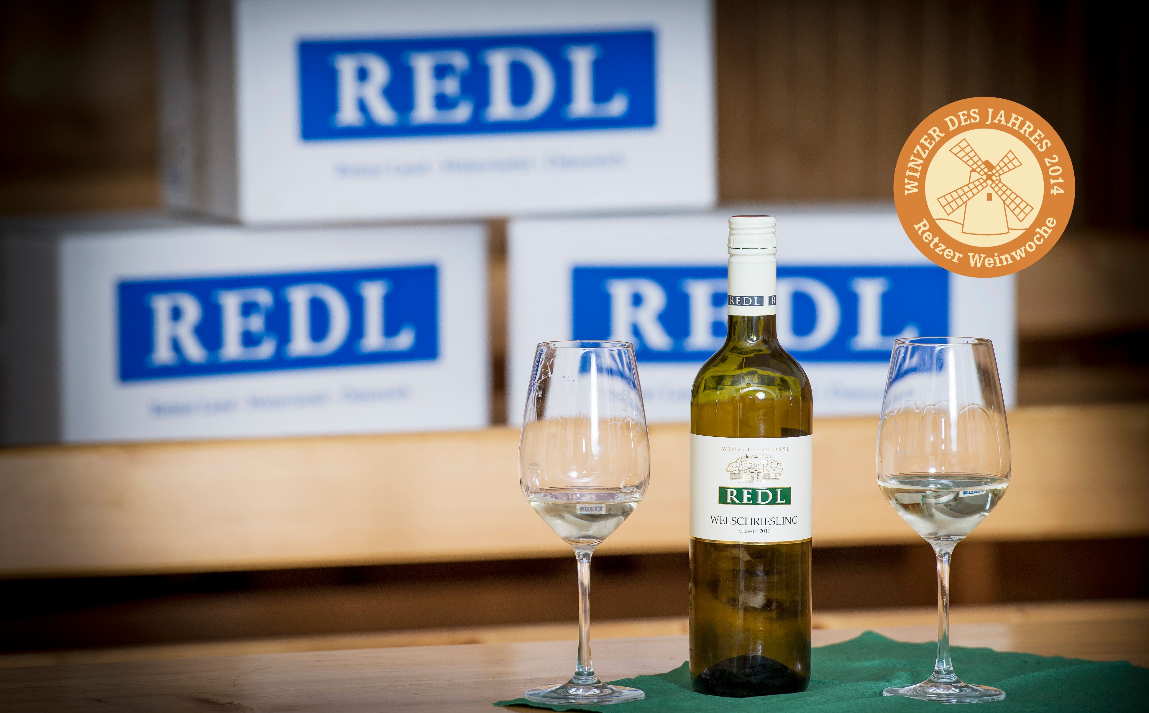 Weinflasche und Gläser vor Redl-Kartons.
