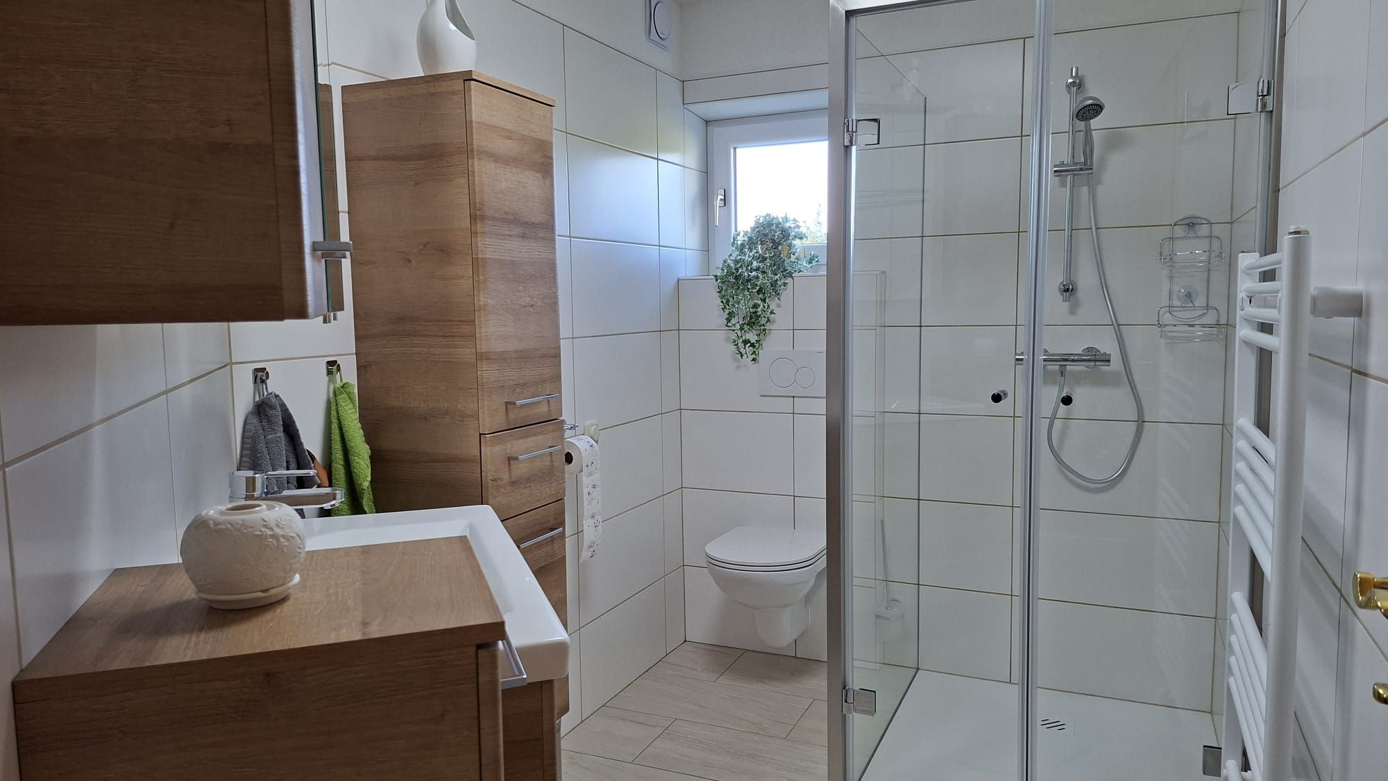 Modernes Badezimmer mit Dusche, WC und Holzschränken.