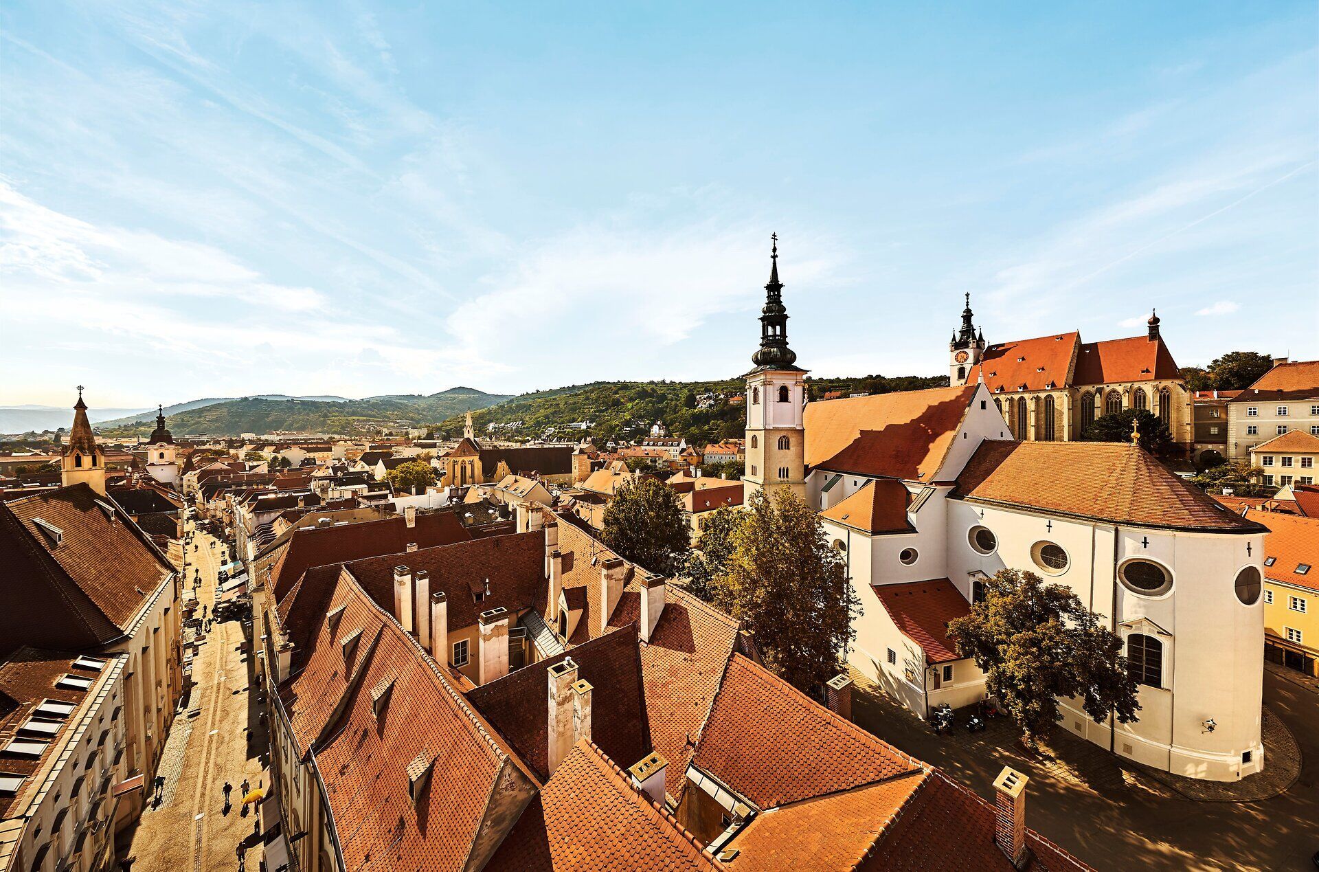 Die Altstadt verzaubert mit ihren charmanten Gassen und historischen Gebäuden, die in warmen Farben erstrahlen. Die sanften Hügel im Hintergrund laden zu Erkundungstouren ein und versprechen unvergessliche Ausblicke.