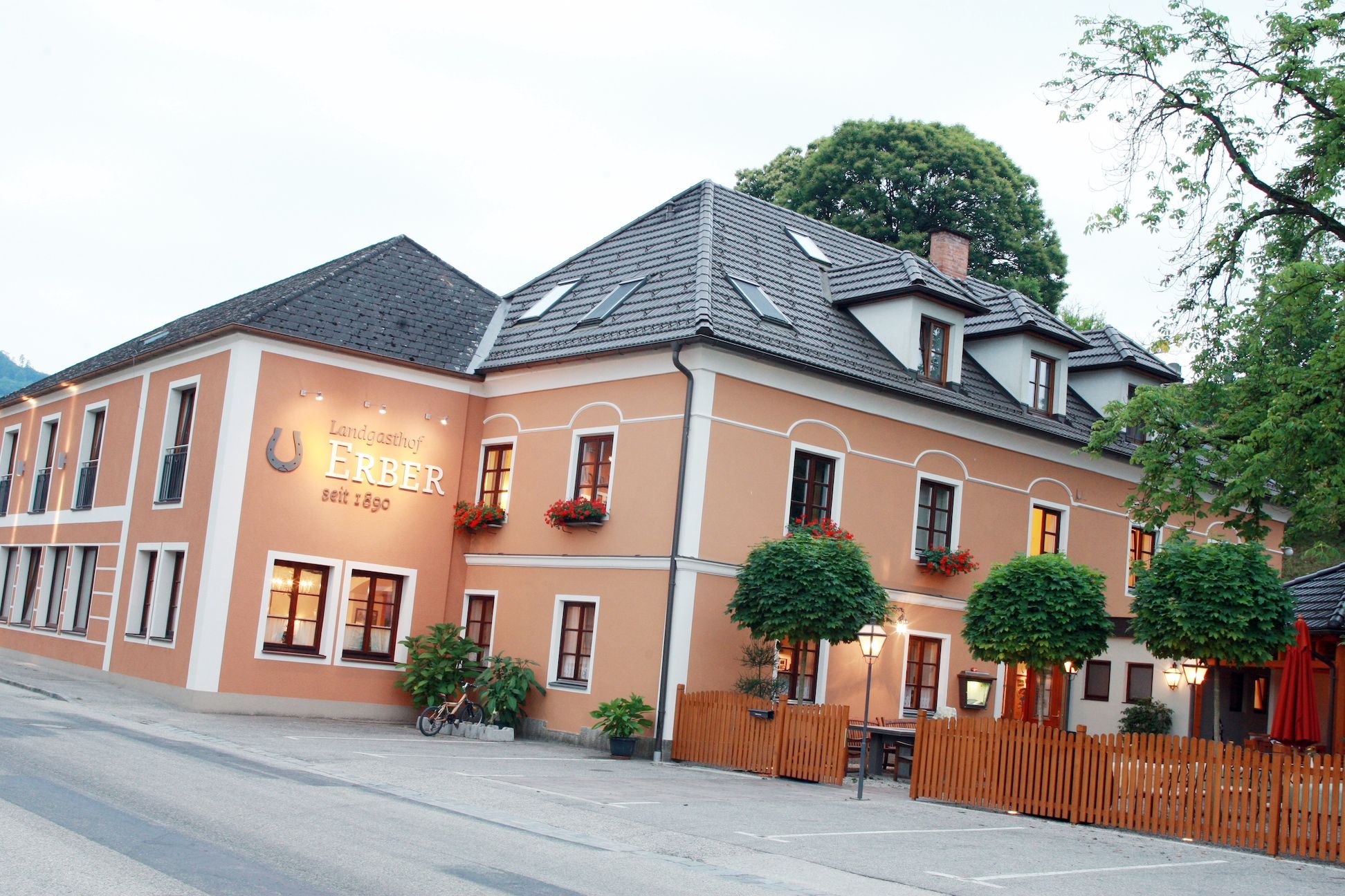 Außenansicht des Landgasthofs Erber mit orangefarbener Fassade und Blumenkästen.