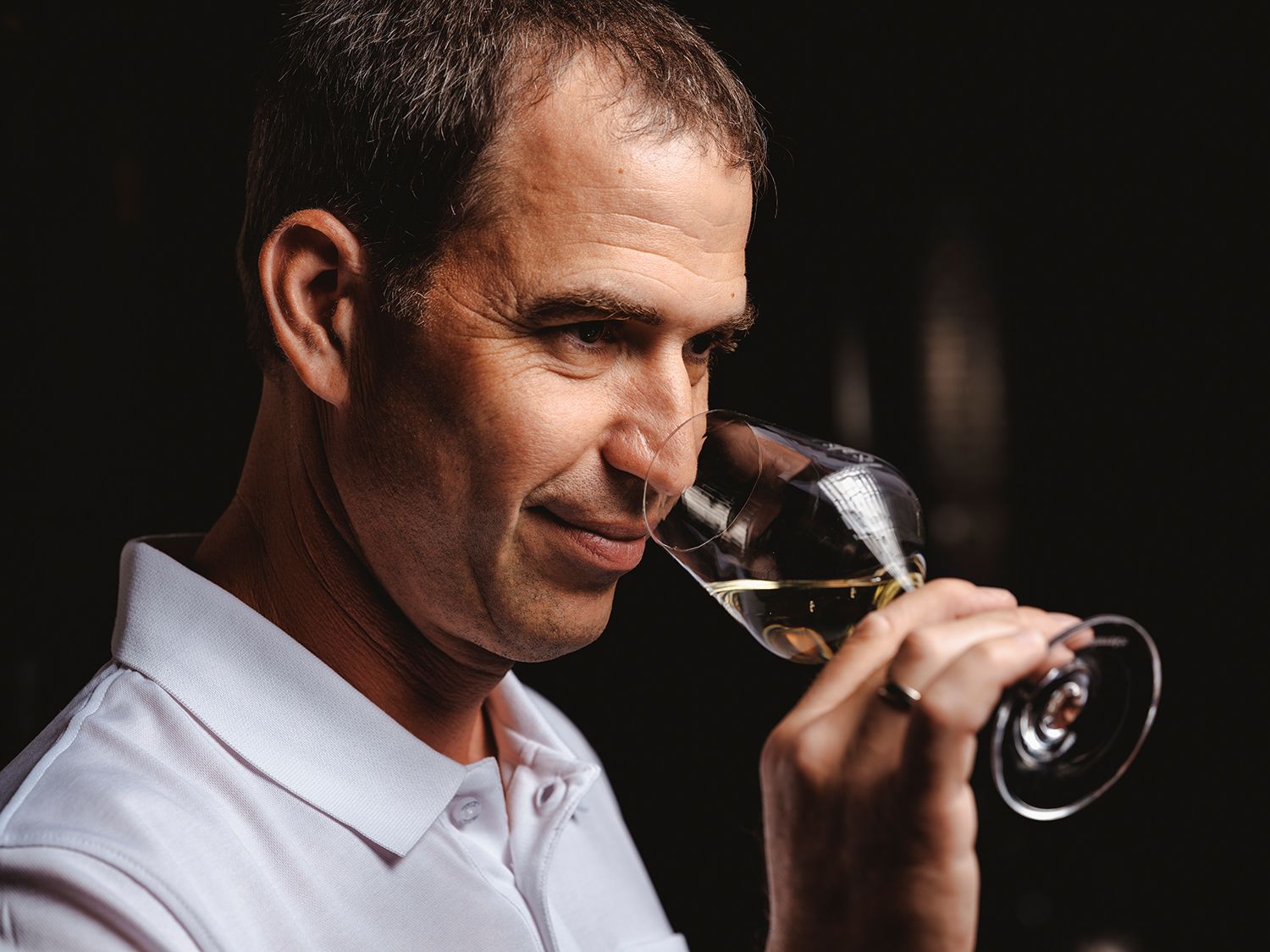 Person riecht an einem Glas Weißwein.