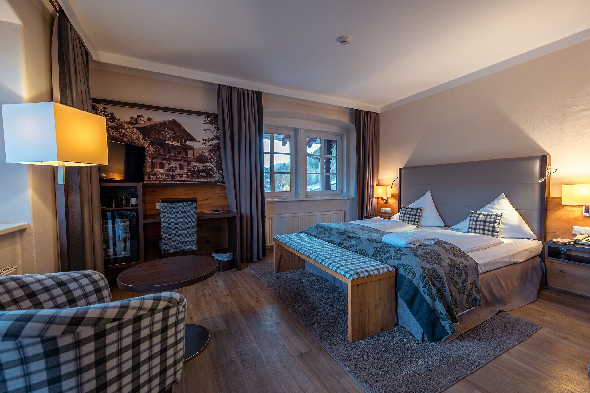 In einem stilvoll eingerichteten Zimmer erwartet Sie eine gemütliche Atmosphäre, die zum Entspannen einlädt. Die warmen Holztöne und die sanfte Beleuchtung schaffen einen perfekten Rückzugsort nach einem erlebnisreichen Tag in den Wiener Alpen. Genießen Sie den Blick auf die umliegende Natur und lassen Sie sich von der Ruhe umhüllen.