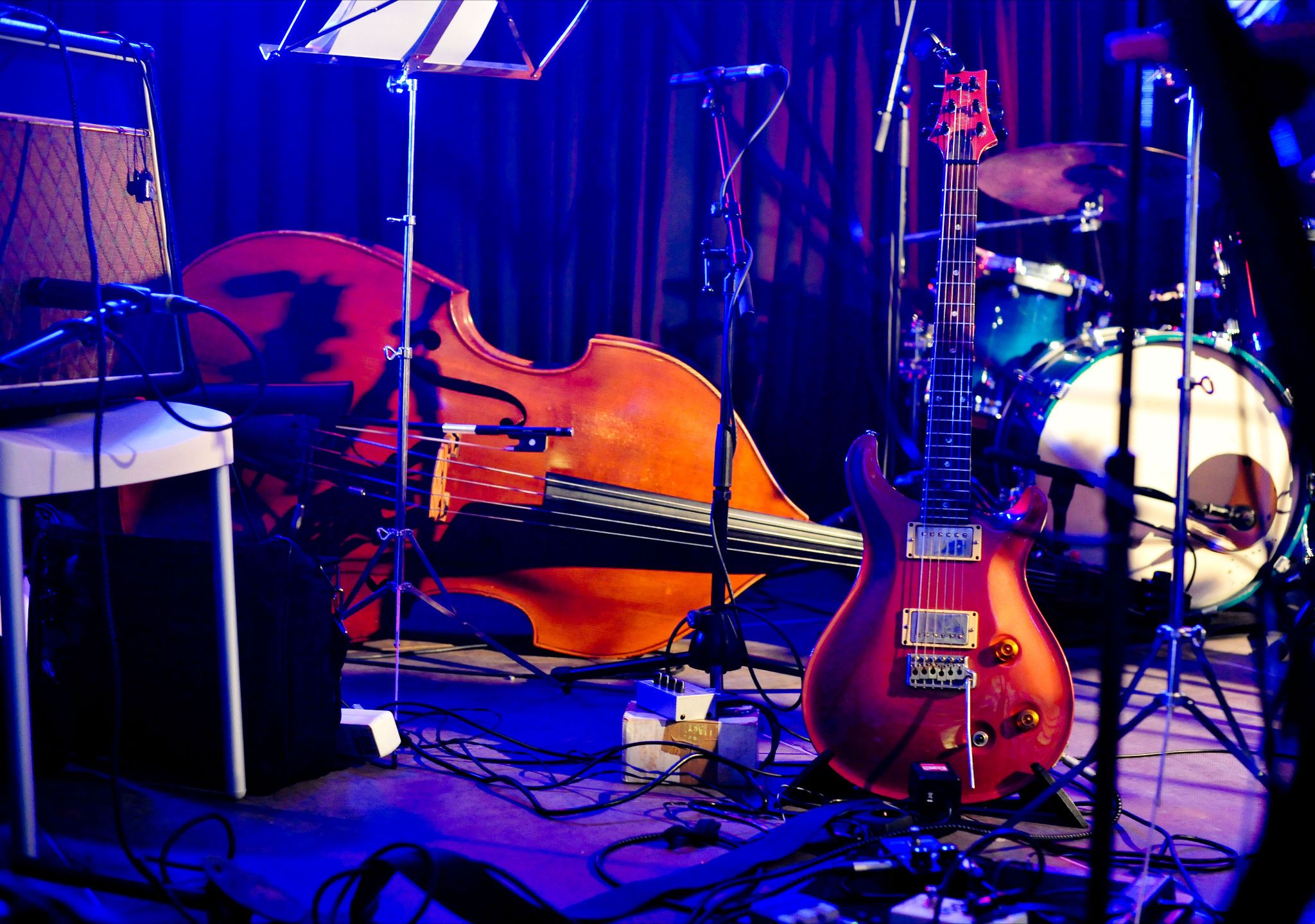 Musikinstrumente auf einer Bühne, darunter eine Gitarre, ein Kontrabass und ein Schlagzeug.