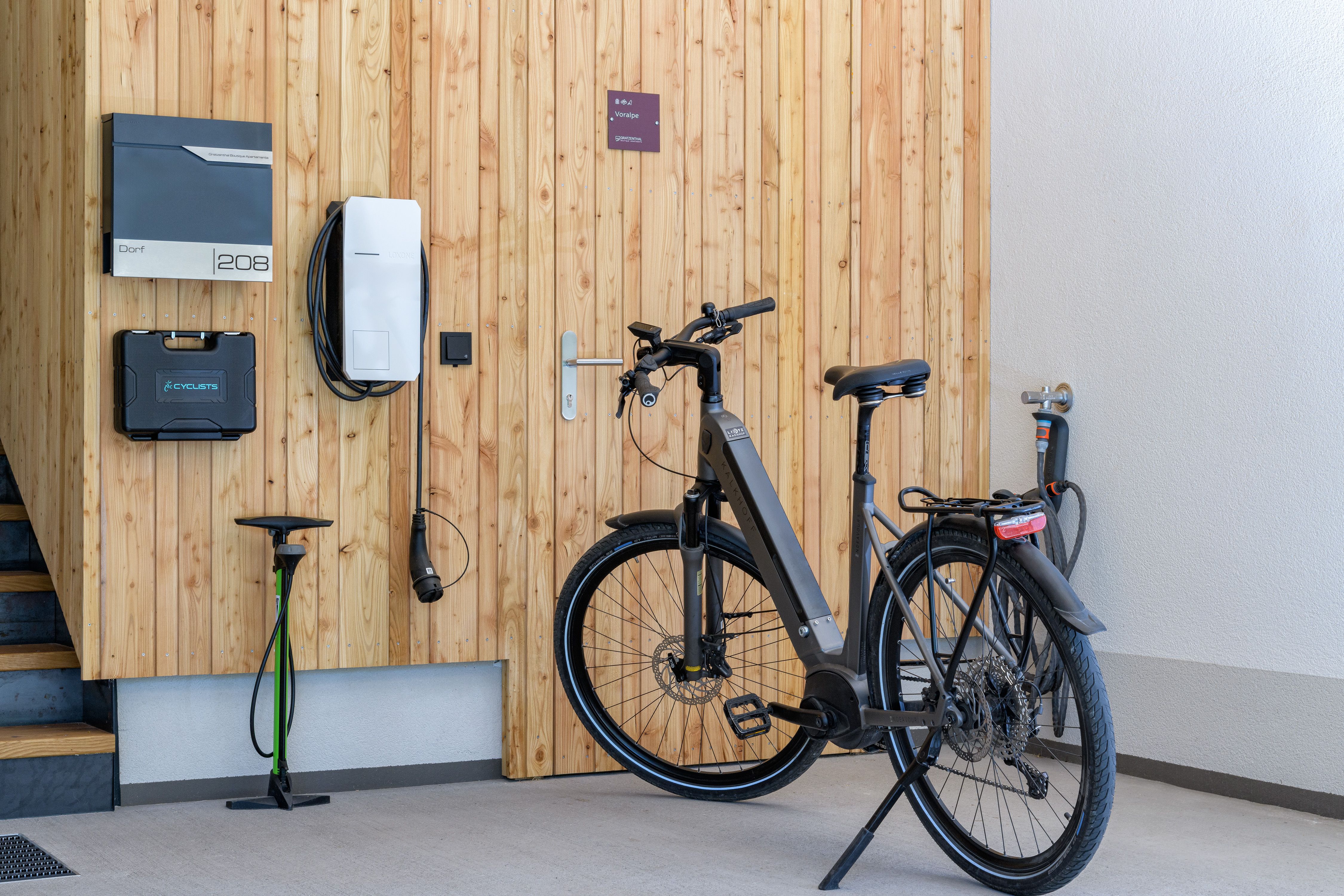 Ein modernes E-Bike steht in einer Garage neben einer Ladestation an einer Holzwand.