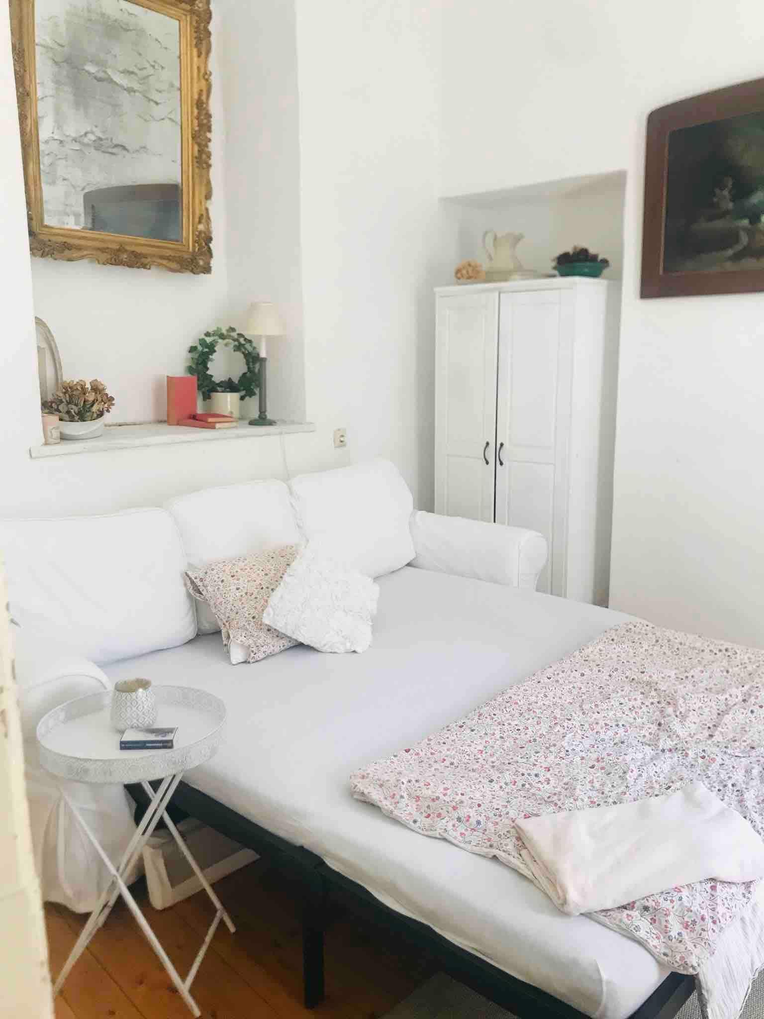 Gemütlicher Schlafbereich mit weißem Sofa, Beistelltisch und dekorativen Elementen.