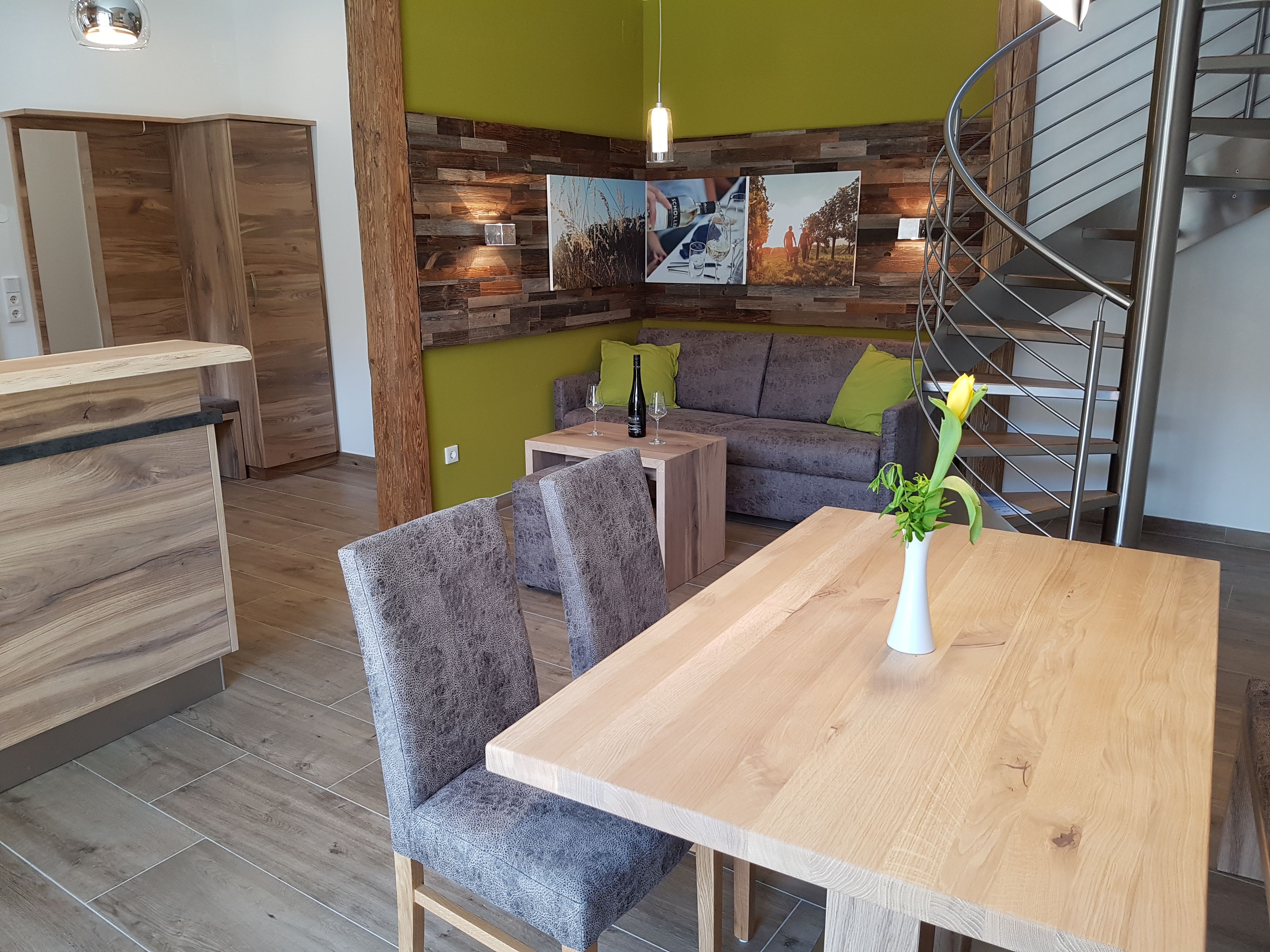 Modernes Appartement mit Holzmöbeln, grauem Sofa, gelber Wand und Wendeltreppe.