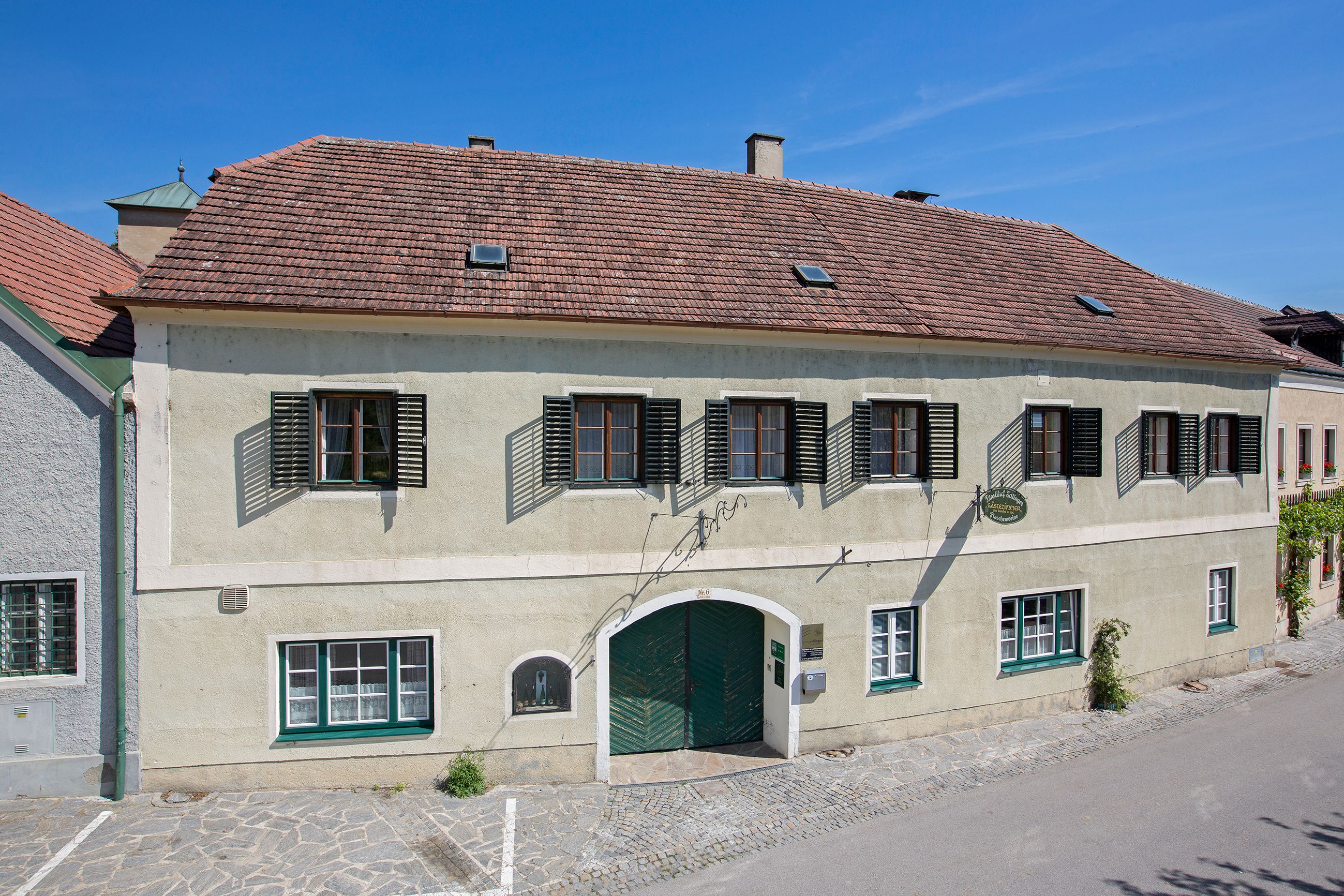 Außenansicht eines traditionellen Gebäudes mit grünem Tor und Fensterläden.